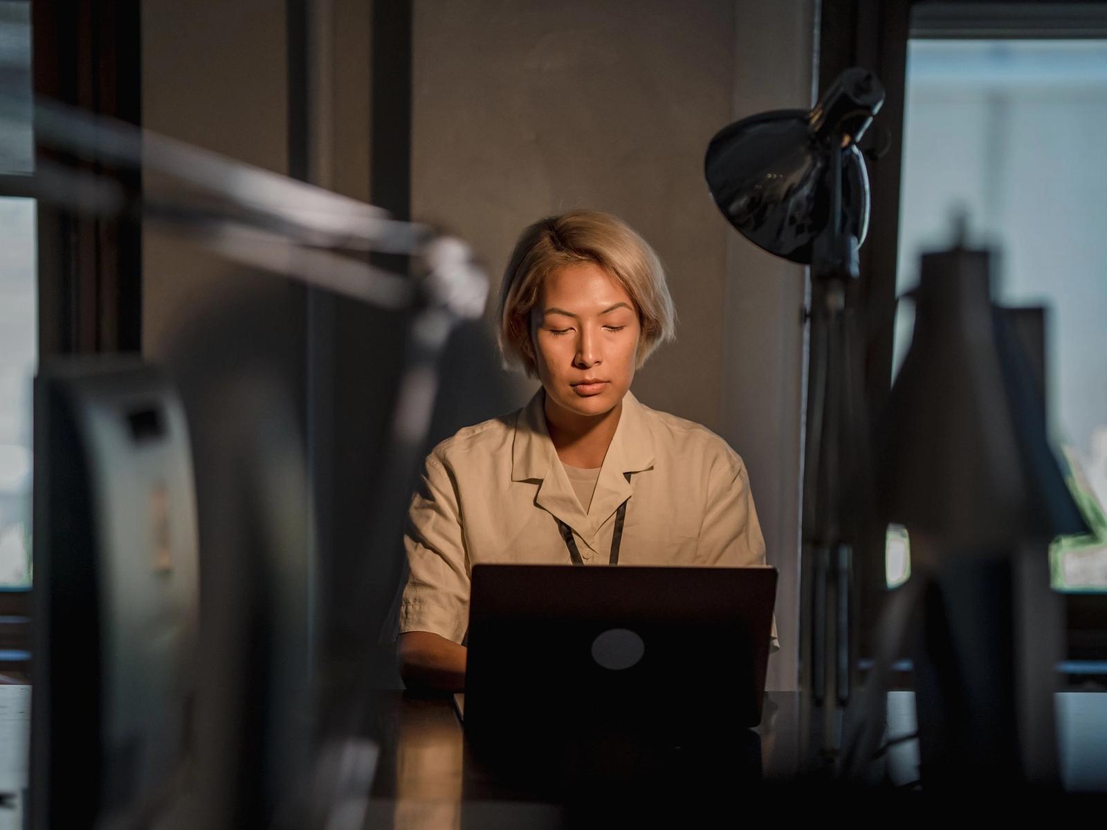 A woman working at a desk in an office at night.