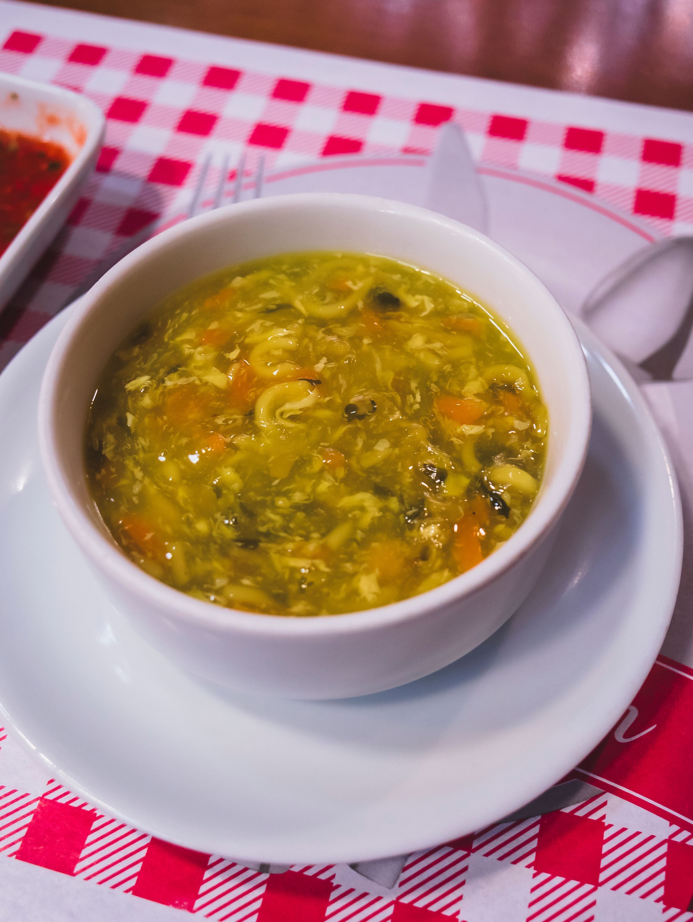 A bowl of soup on a white saucer.