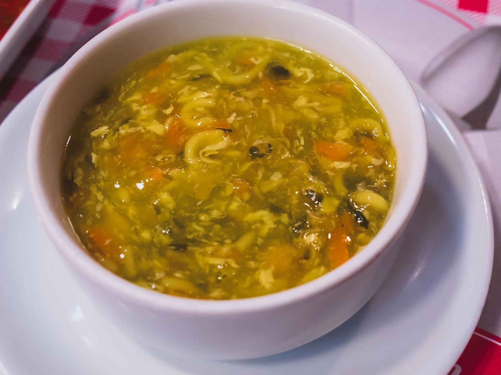 A bowl of soup on a white saucer.