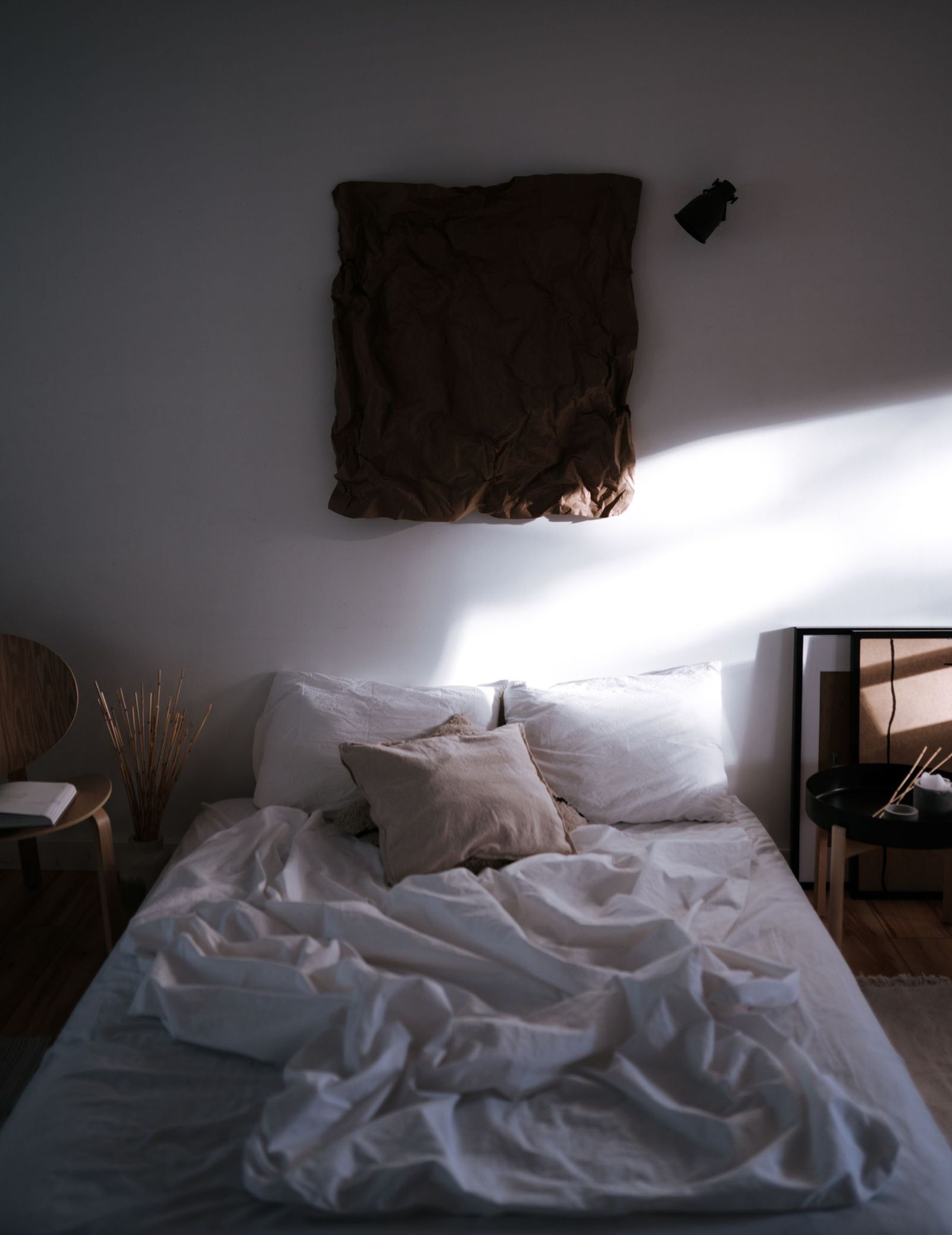 A bed with white sheets beside a window.