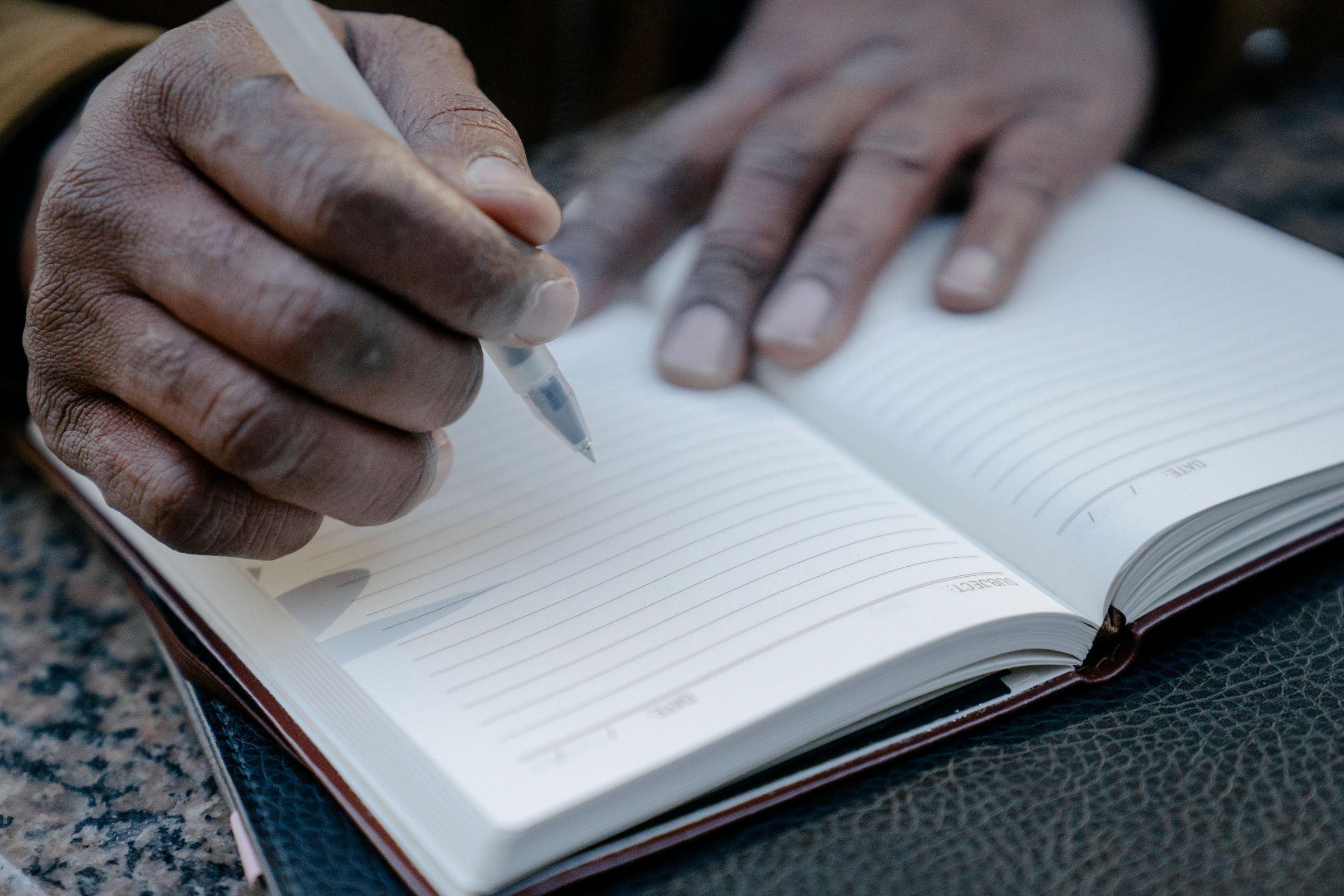 Hands writing in an open notebook.