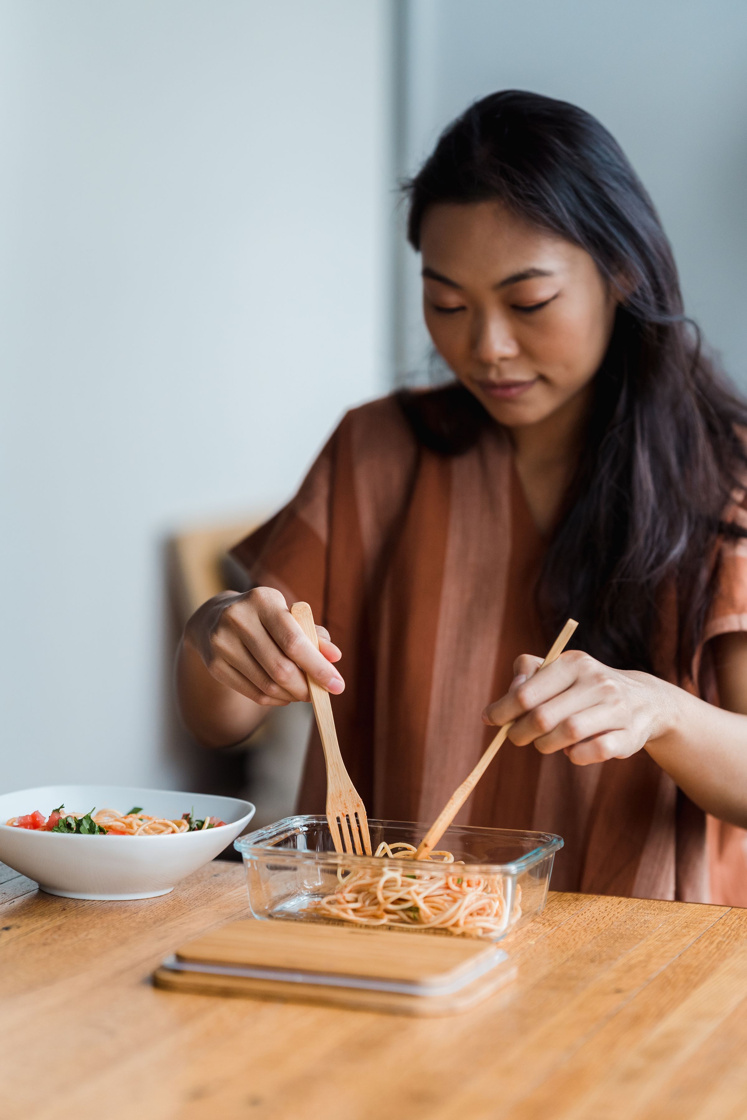 Hands serving pasta at a table.