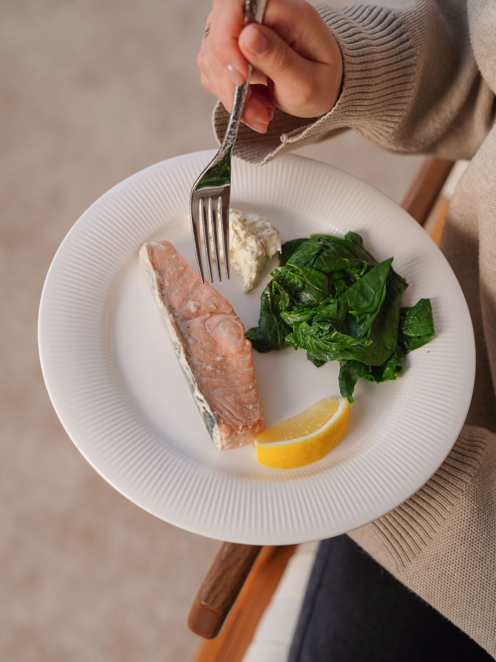 A plate of salmon, leafy greens and lemon.