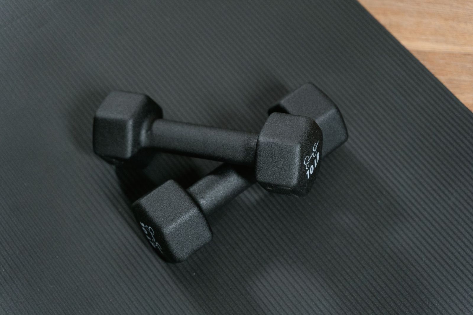 Two black dumbbells on an exercise mat.