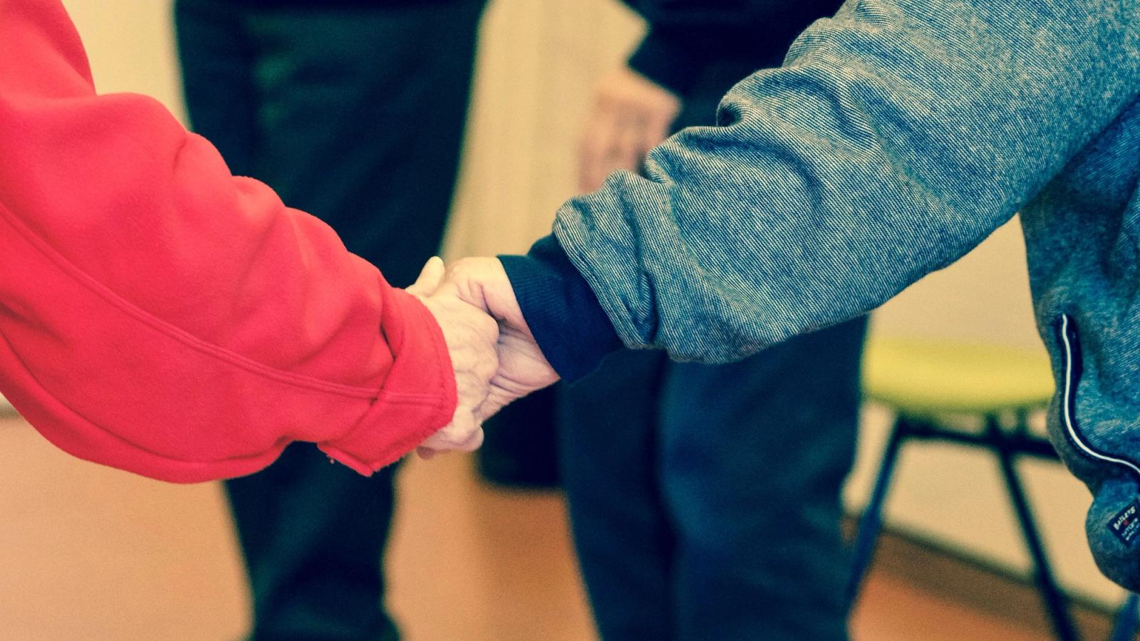 One person gently holding another person’s hands.