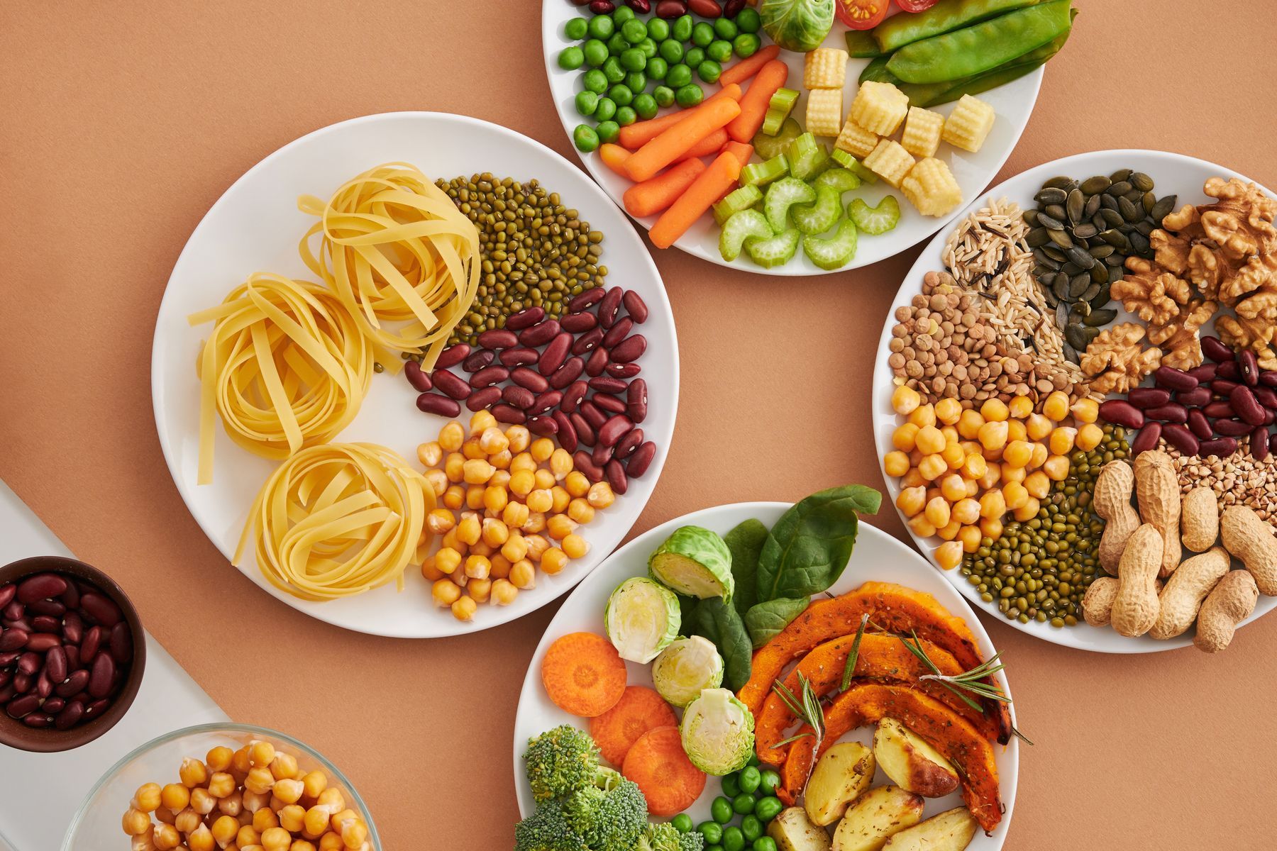 Plates of vegetables, nuts, grains and pasta.