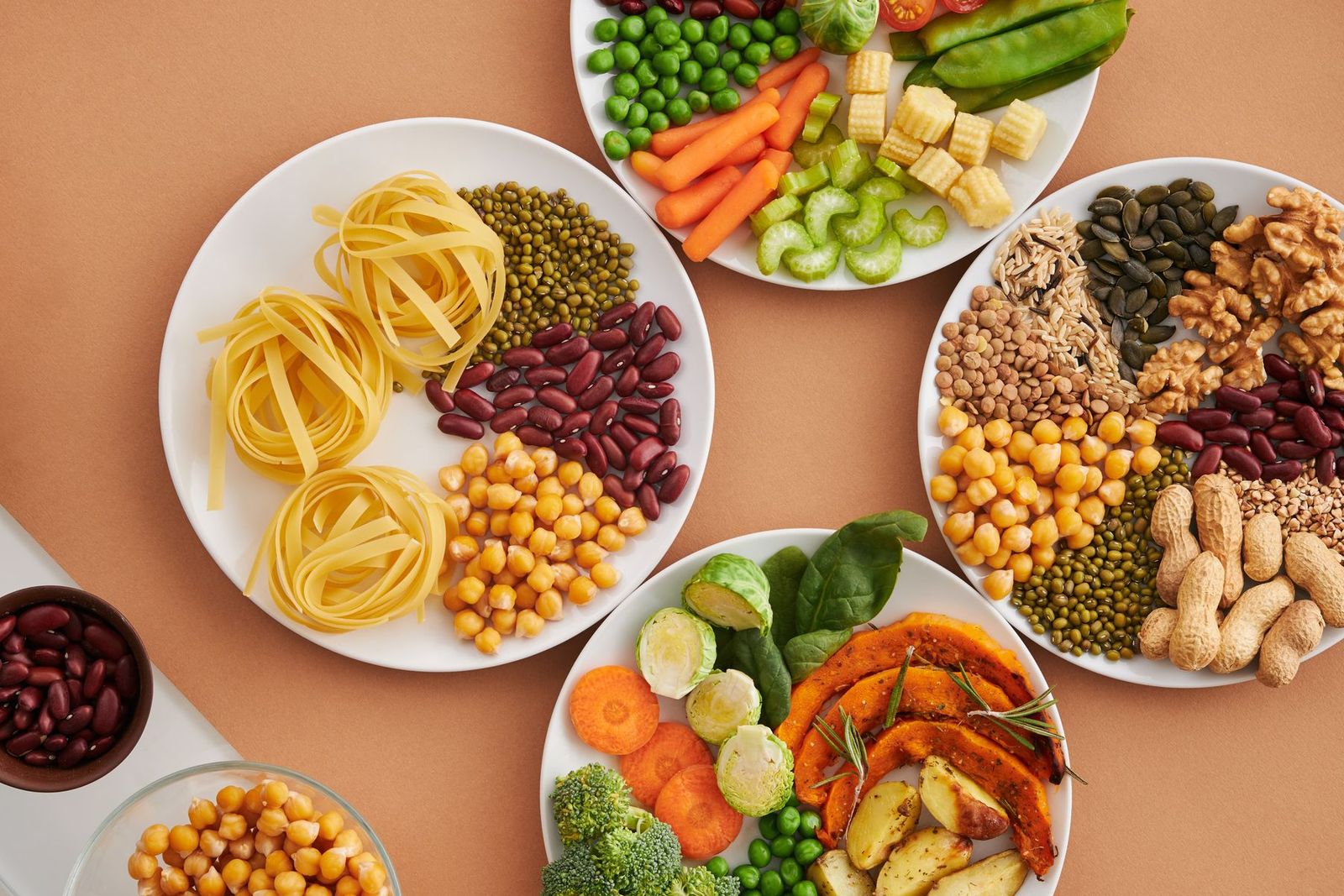 Plates of vegetables, nuts, grains and pasta.