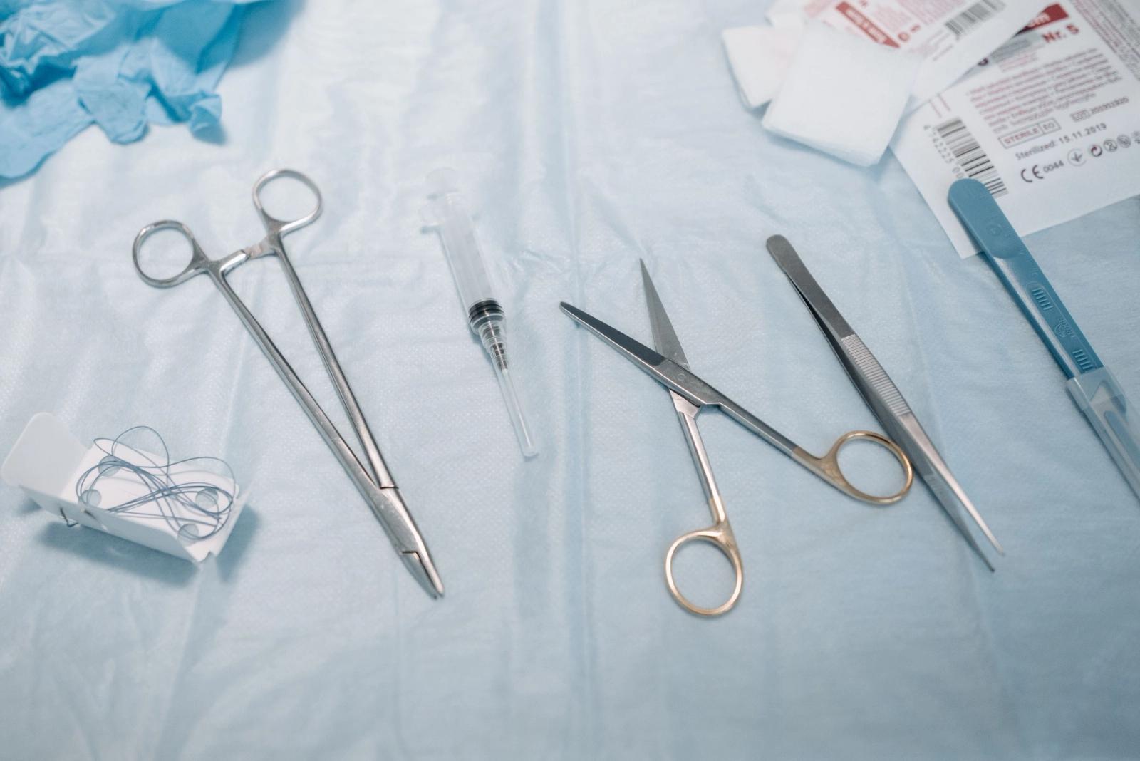Metal medical instruments laid out on a blue drape.