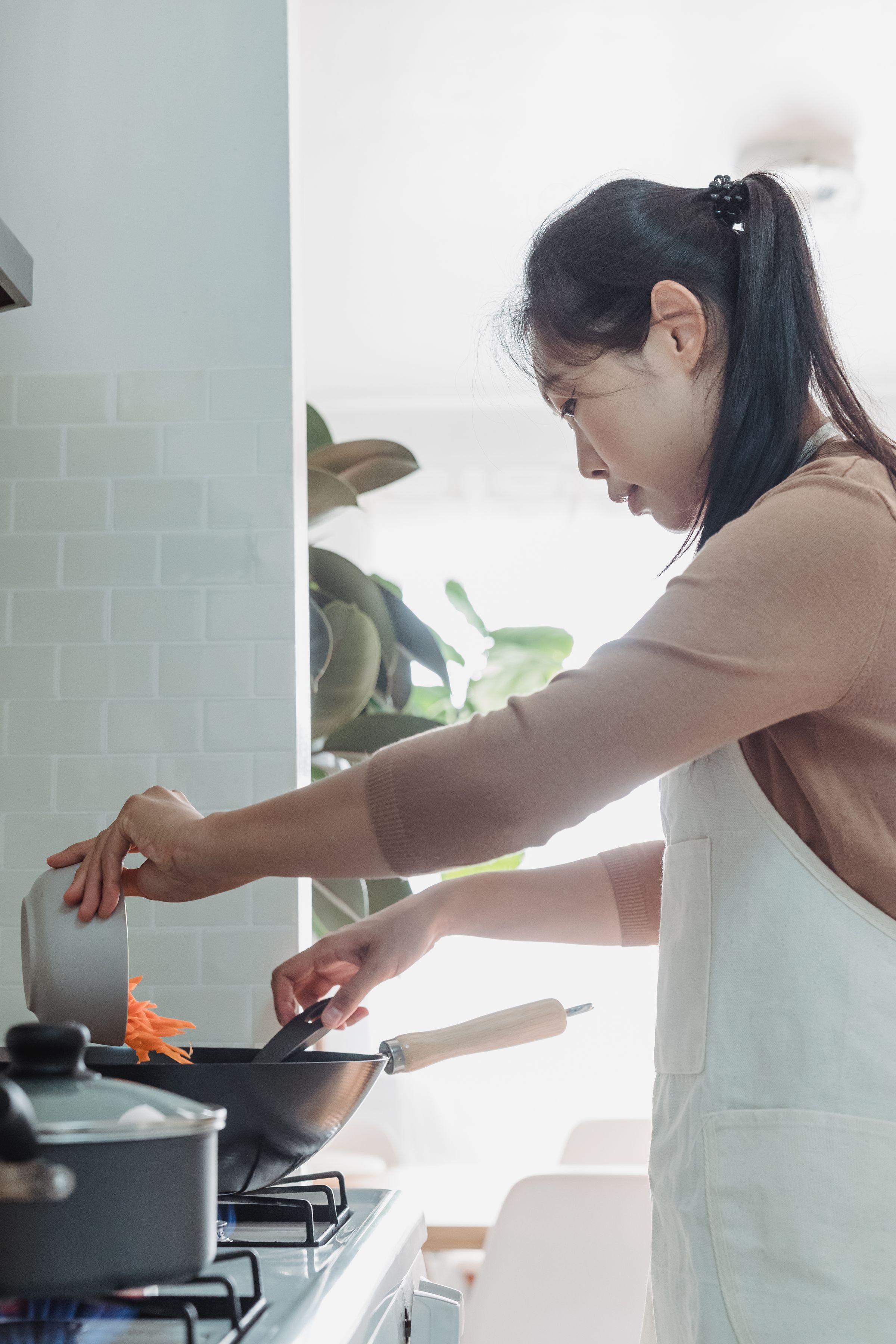 Hands stirring food in a pan at a cooker.
