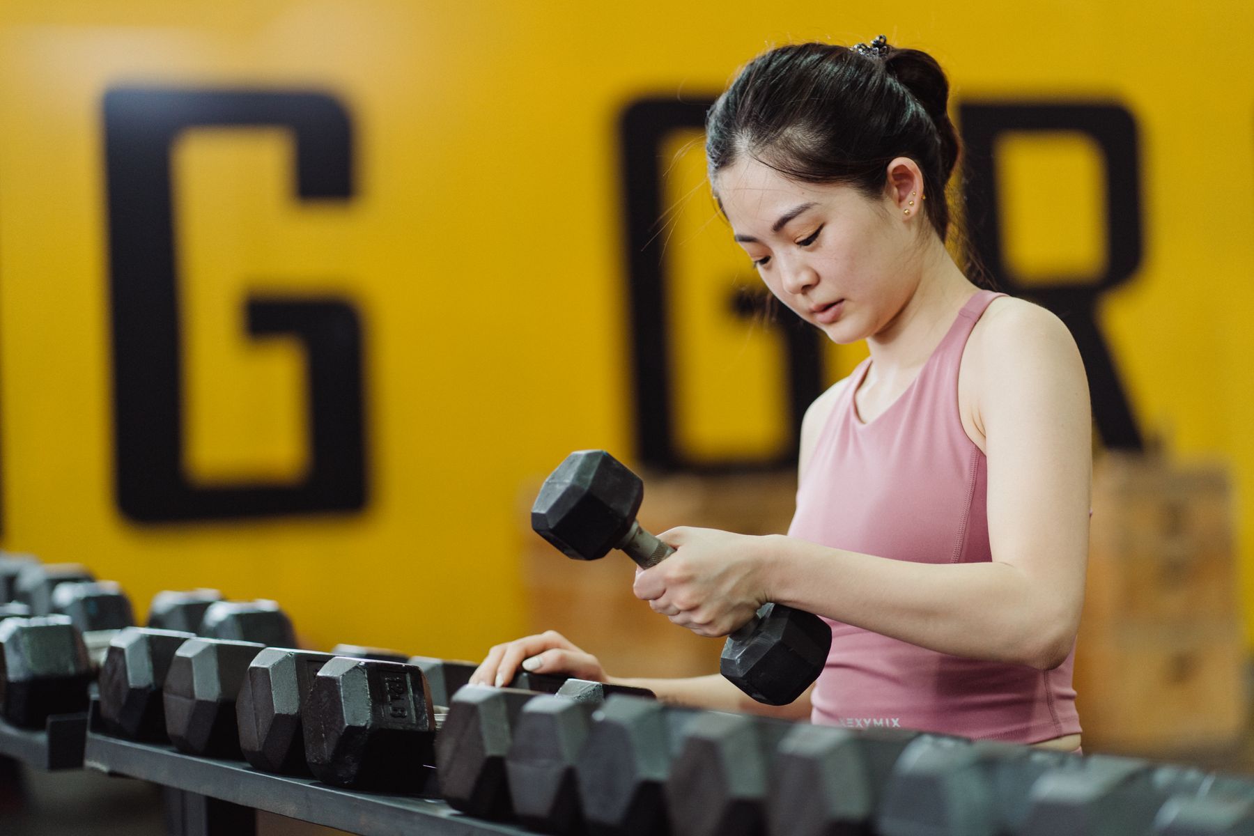 A woman lifting a dumbbell in a gym.