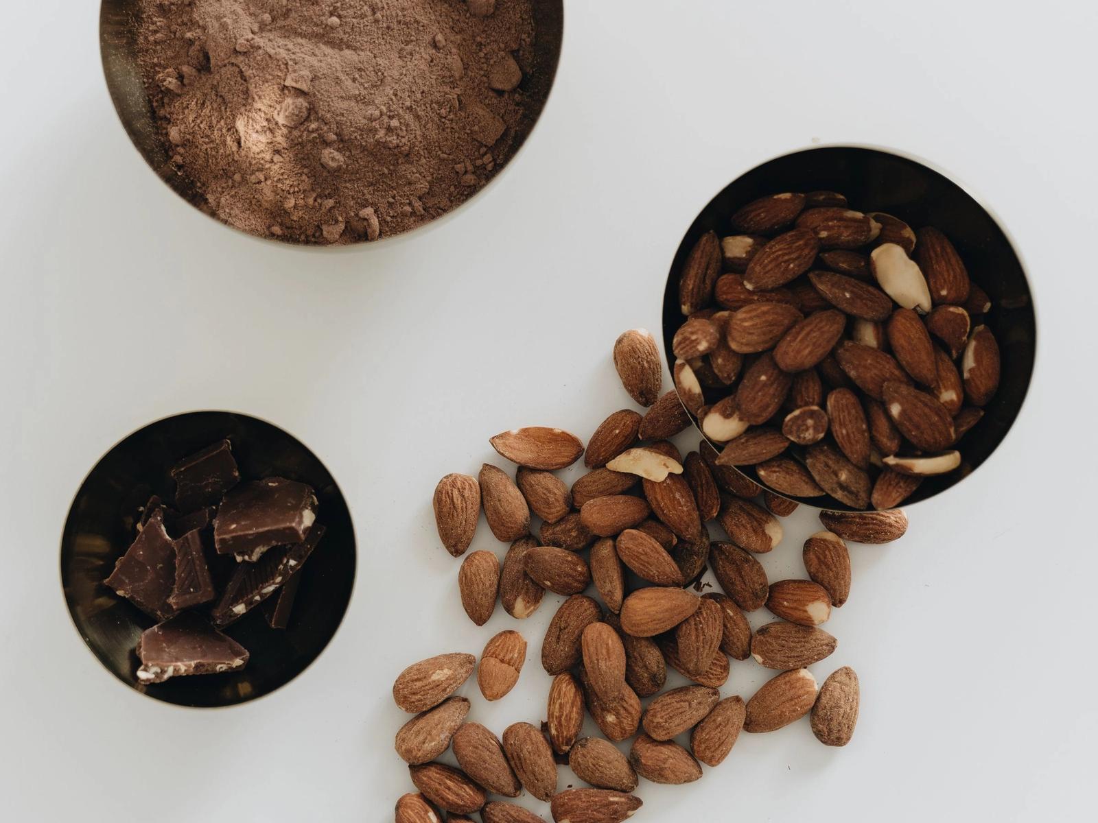 Almonds and pieces of chocolate on a light background.