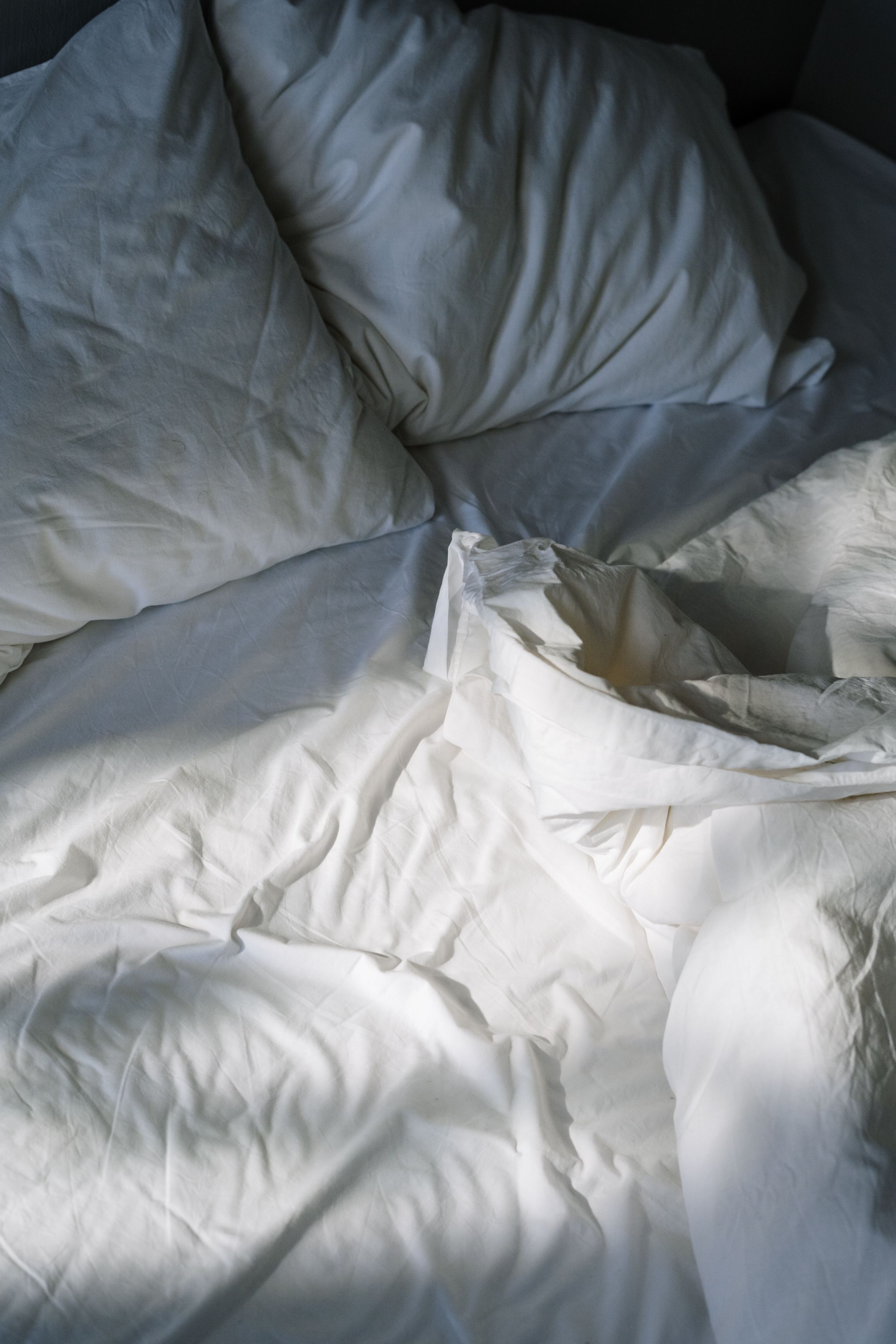 White pillows and sheets on an empty bed.