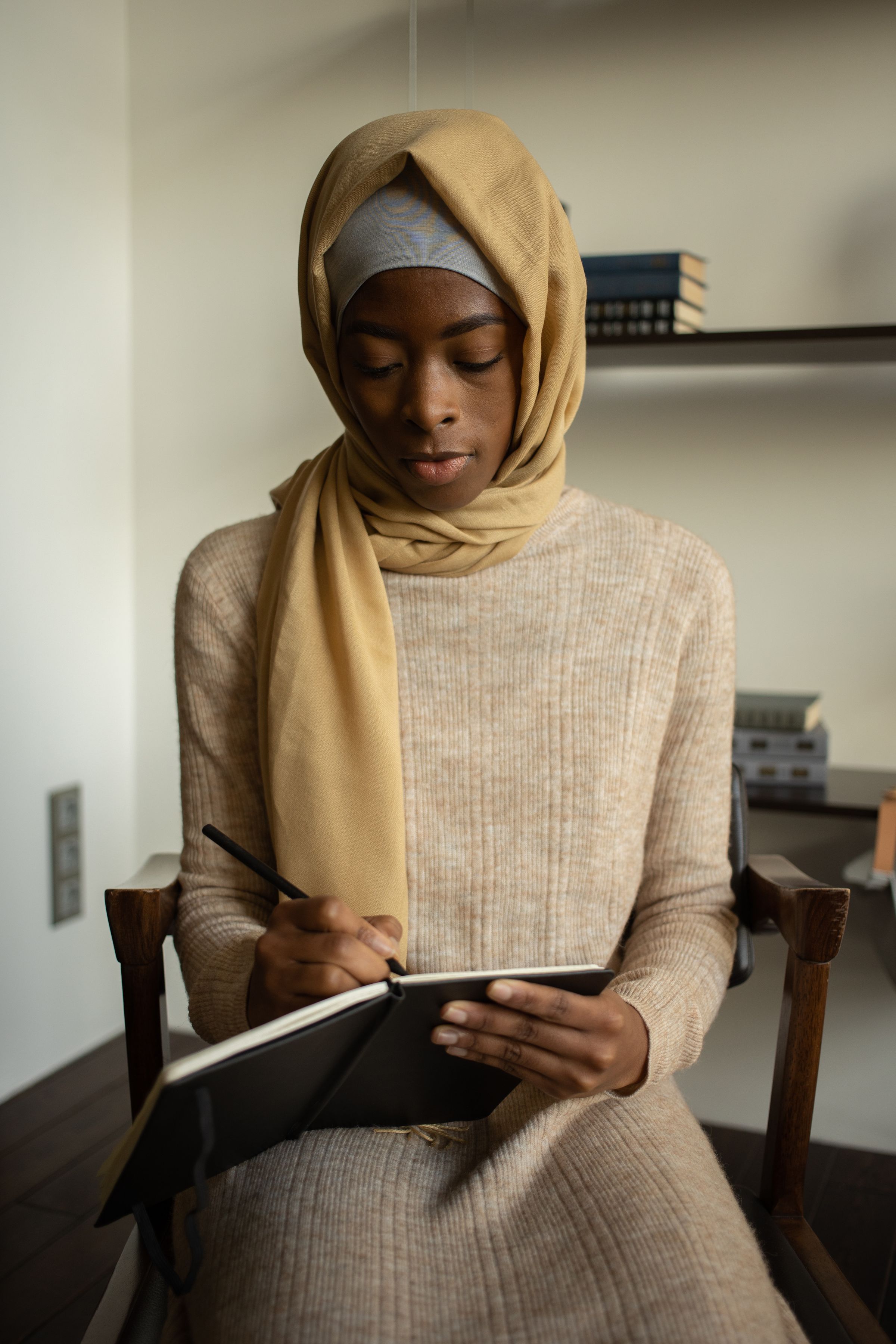 A woman in a headscarf looking down.