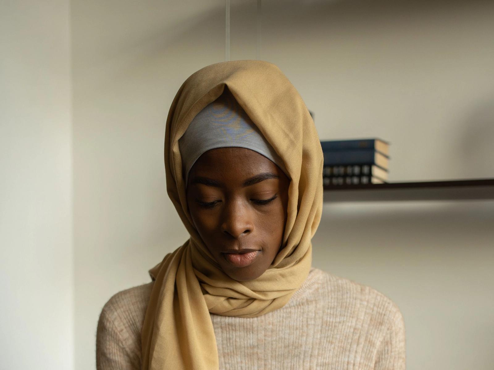 A woman in a headscarf looking down.