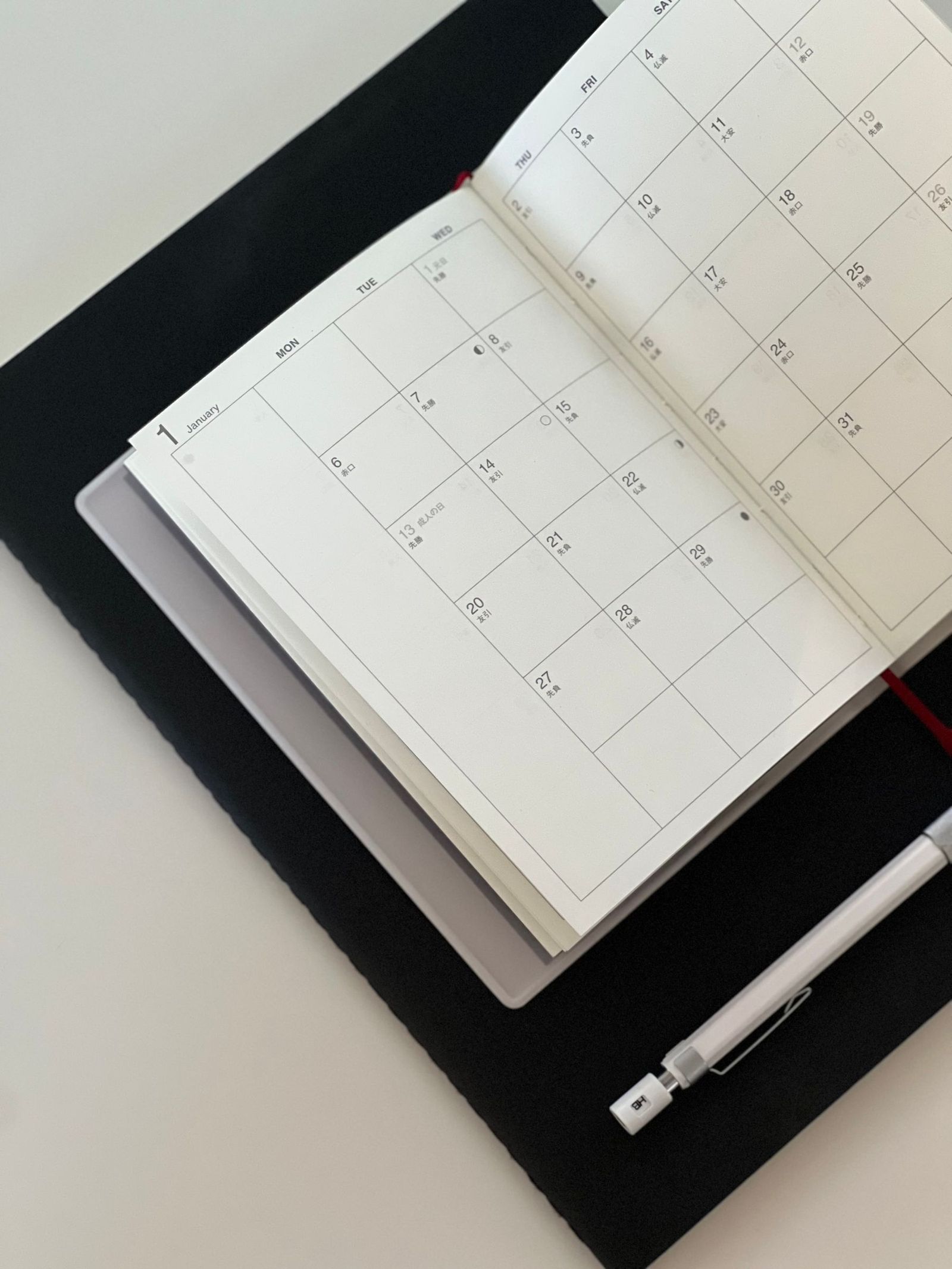 An open calendar and notebook on a desk.