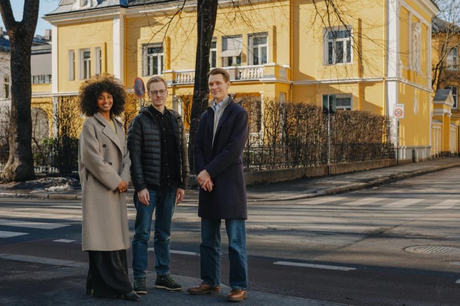 tre personer foran bygg