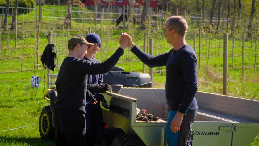 tre personer og en traktor på en gård