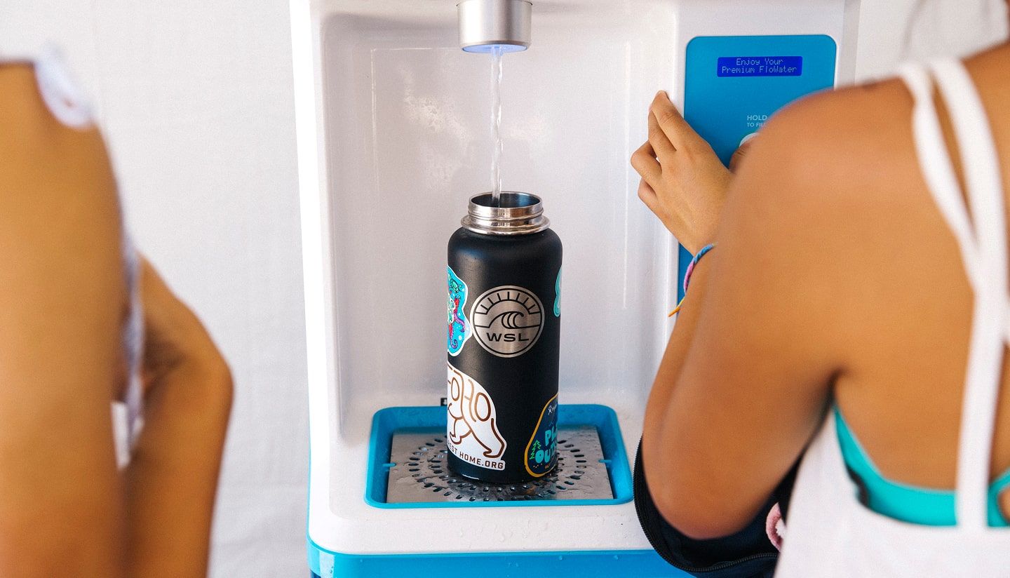 Person filling a glass with ice water from an office water dispenser