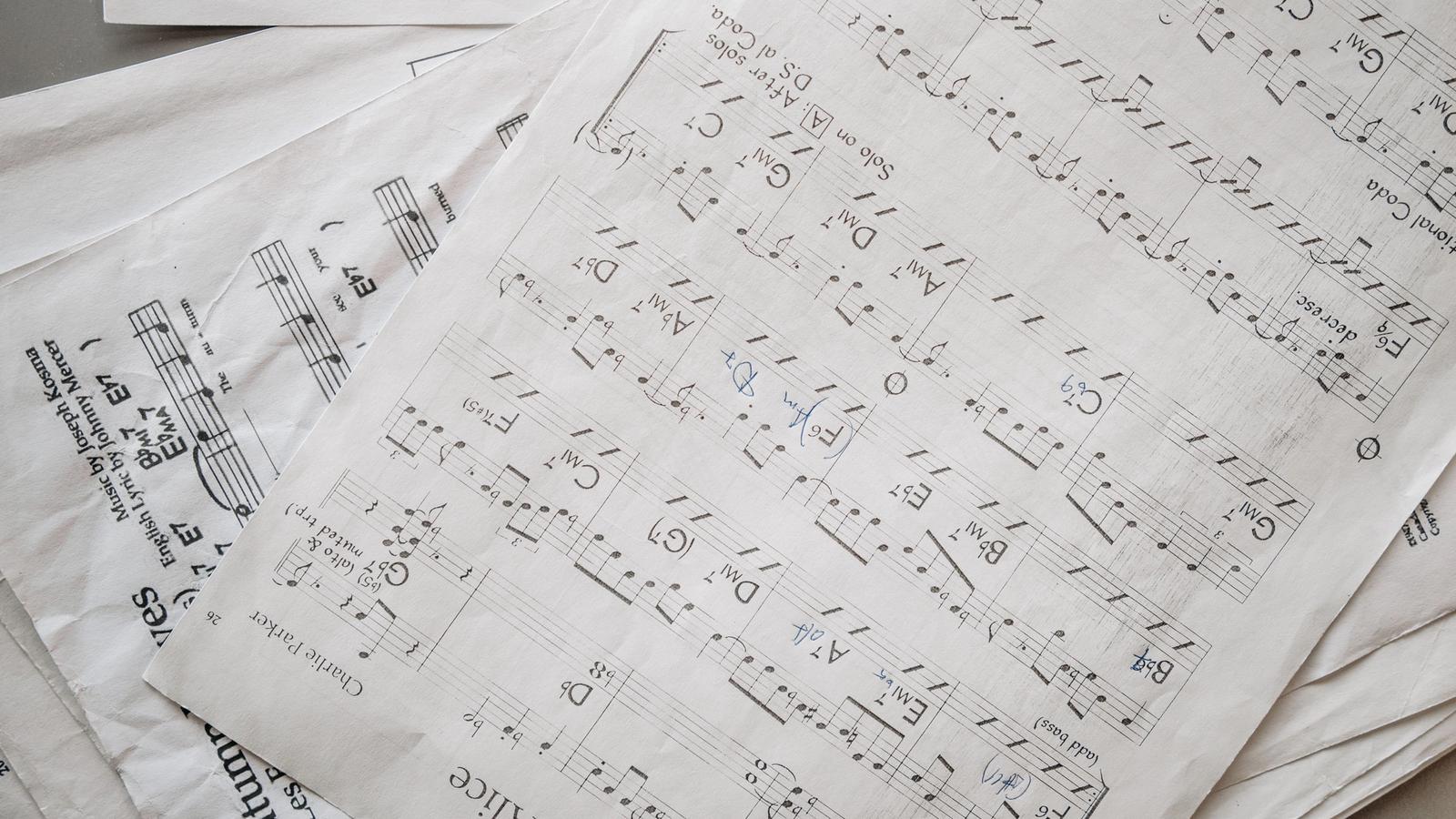 Overlapping jazz lead sheets with chord symbols like Gm7, C7 and Fmaj7 above the staves, some marked up in blue pen.