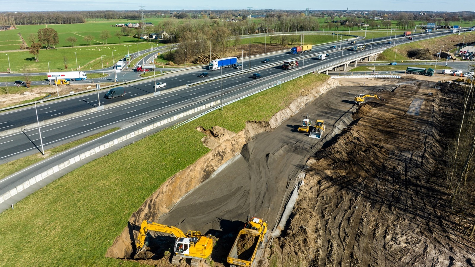 Luchtfoto van snelwegverbreding met graafwerkzaamheden naast bestaande rijbanen