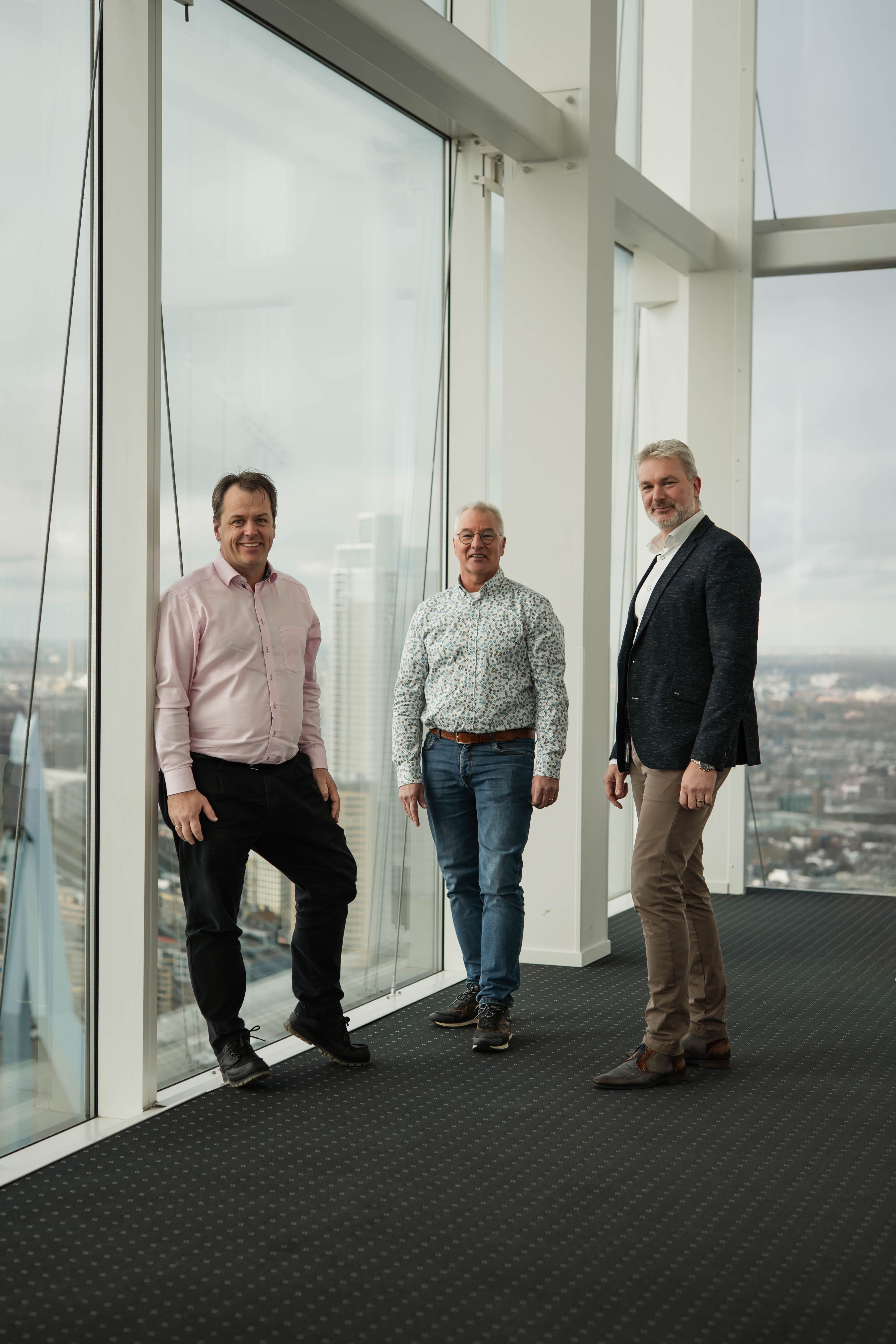 Pieter, Rien en Menno voor glas wat uitkijkt op Rotterdam