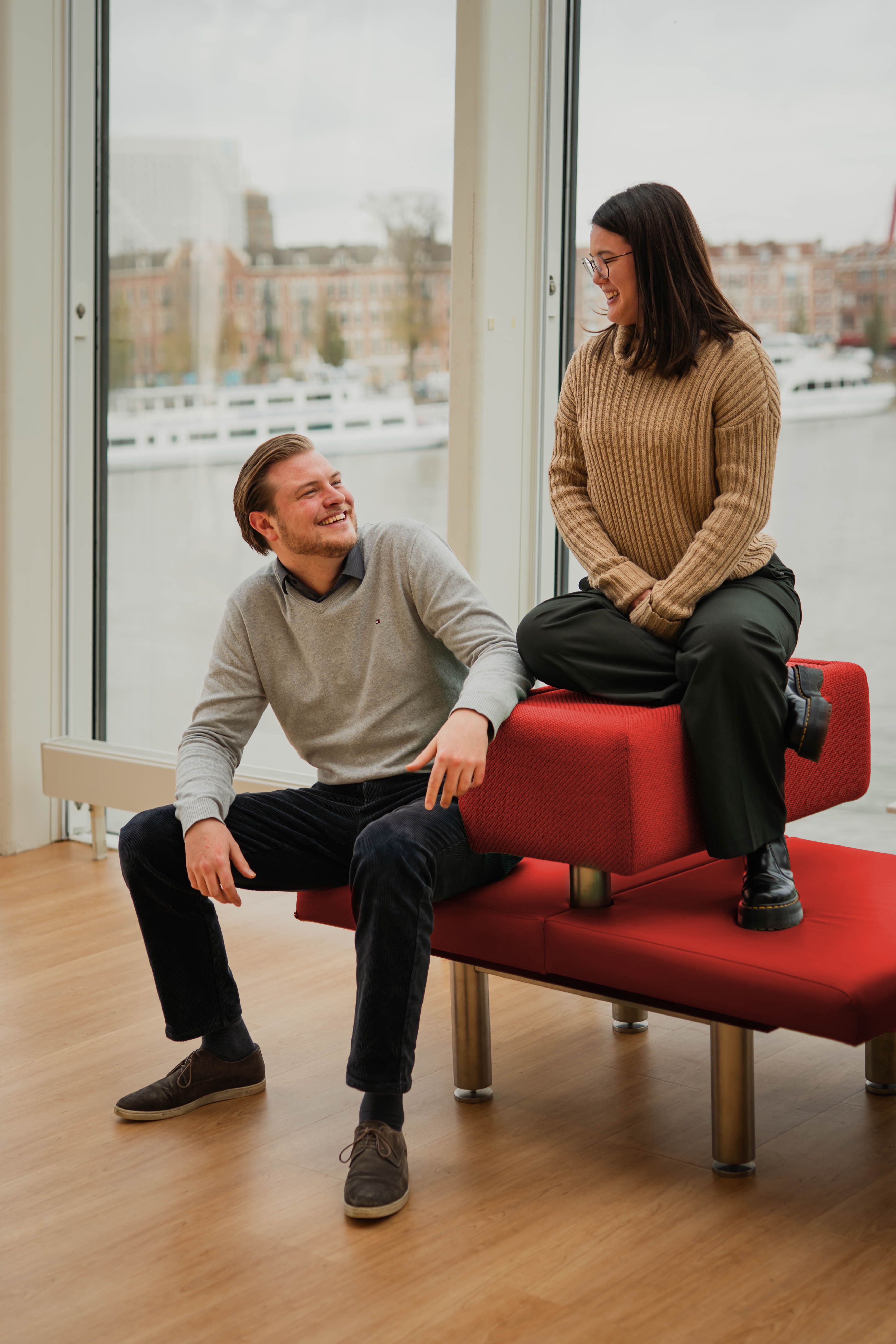 Martijn en Nicole op een rood bankje met uitzicht op Rotterdam