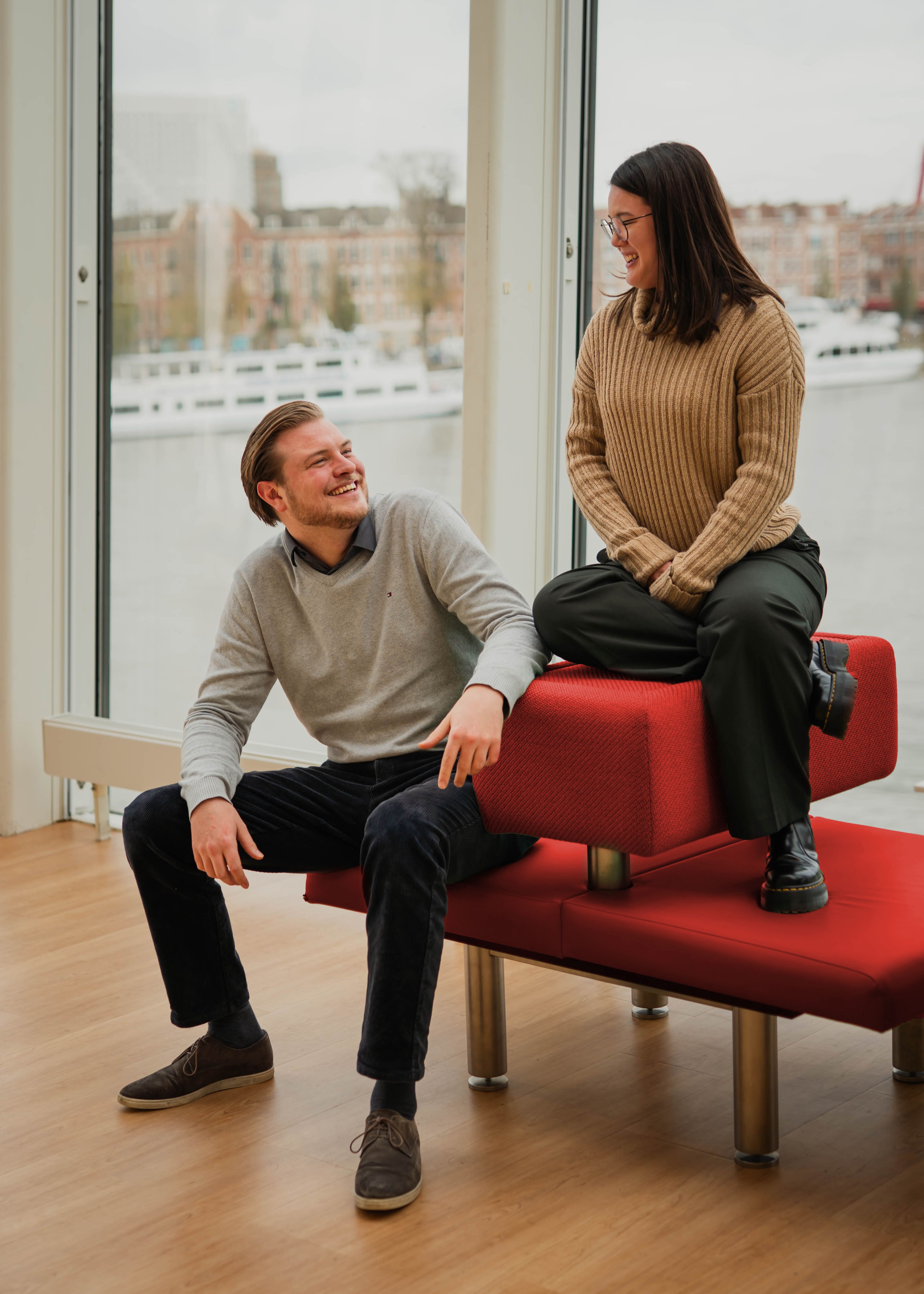 Martijn en Nicole op een rood bankje met uitzicht op Rotterdam