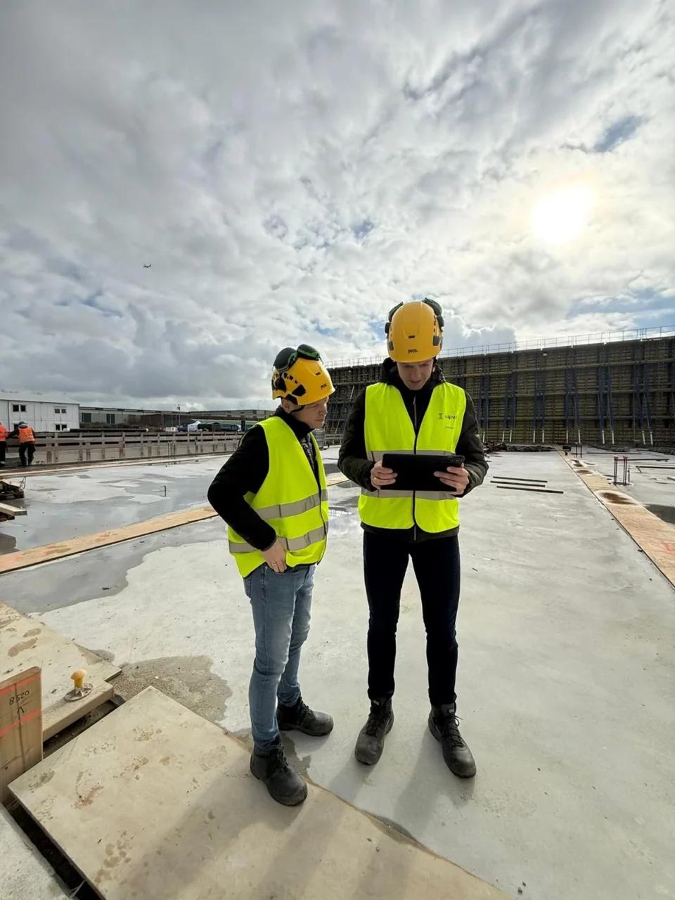 Twee mensen bouwhelmen en vestjes op een bouwgrond