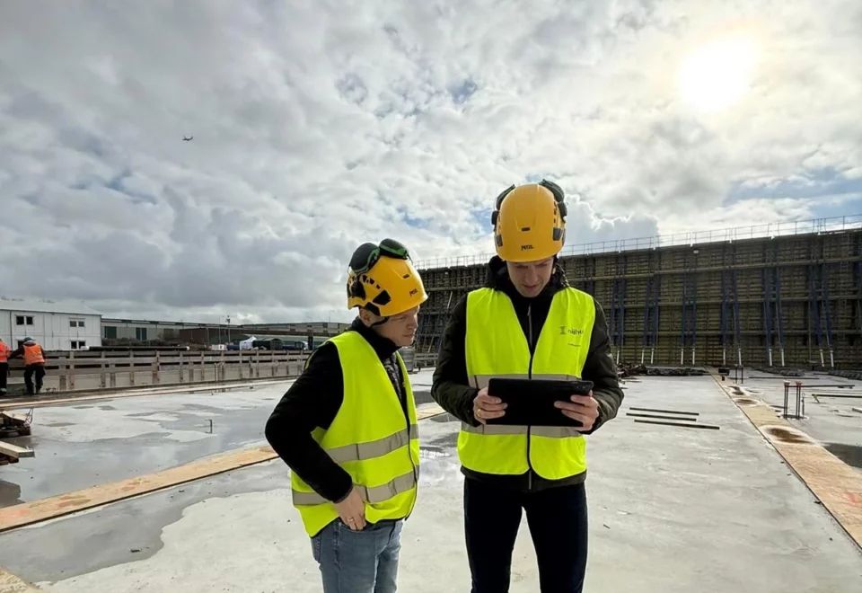 Twee mensen bouwhelmen en vestjes op een bouwgrond
