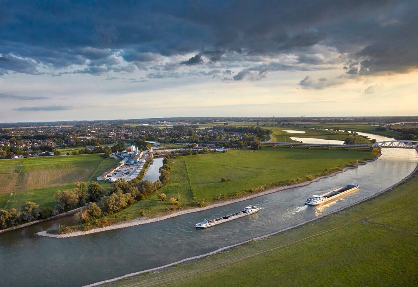 Luchtfoto van rivier met binnenvaartschepen door groen landschap
