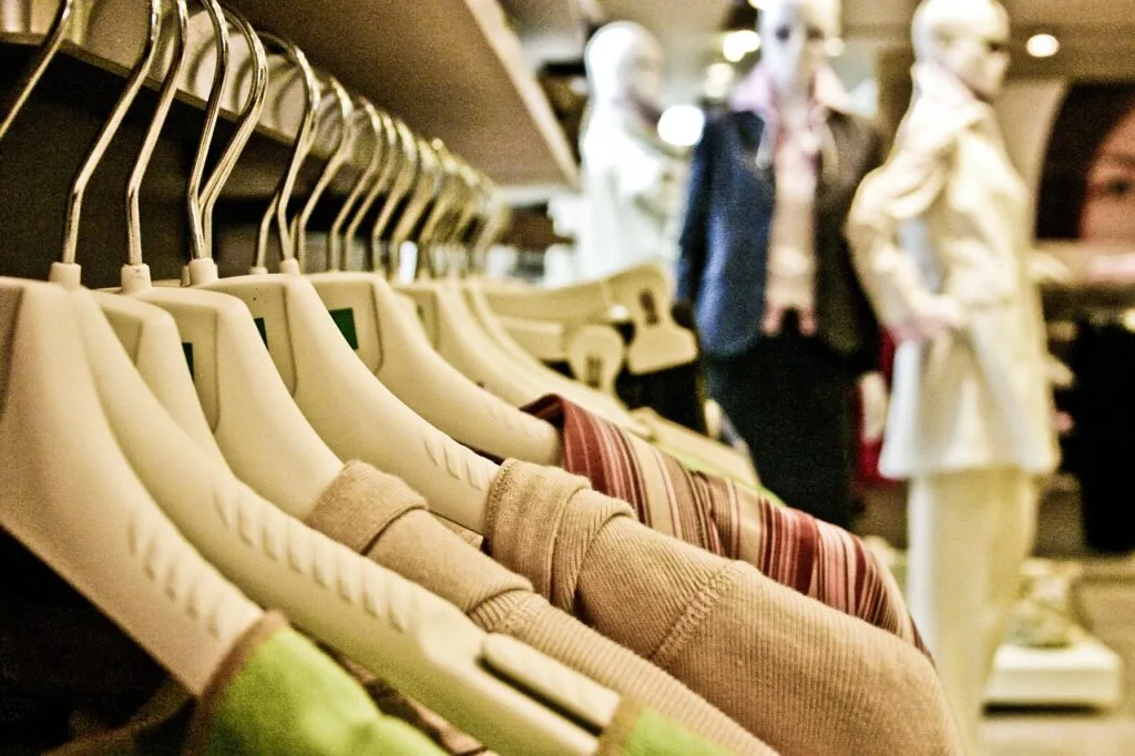 Binnenkant van kledingwinkel. Kledinghangers met kleding en paspoppen
