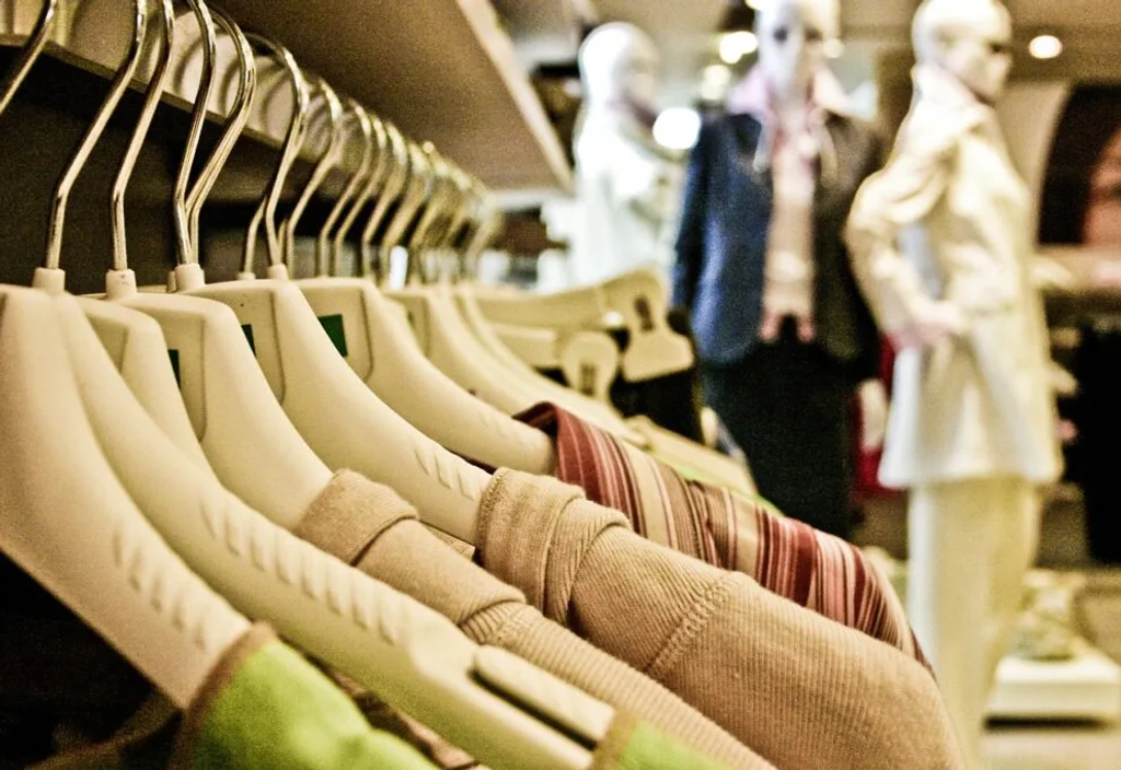 Binnenkant van kledingwinkel. Kledinghangers met kleding en paspoppen