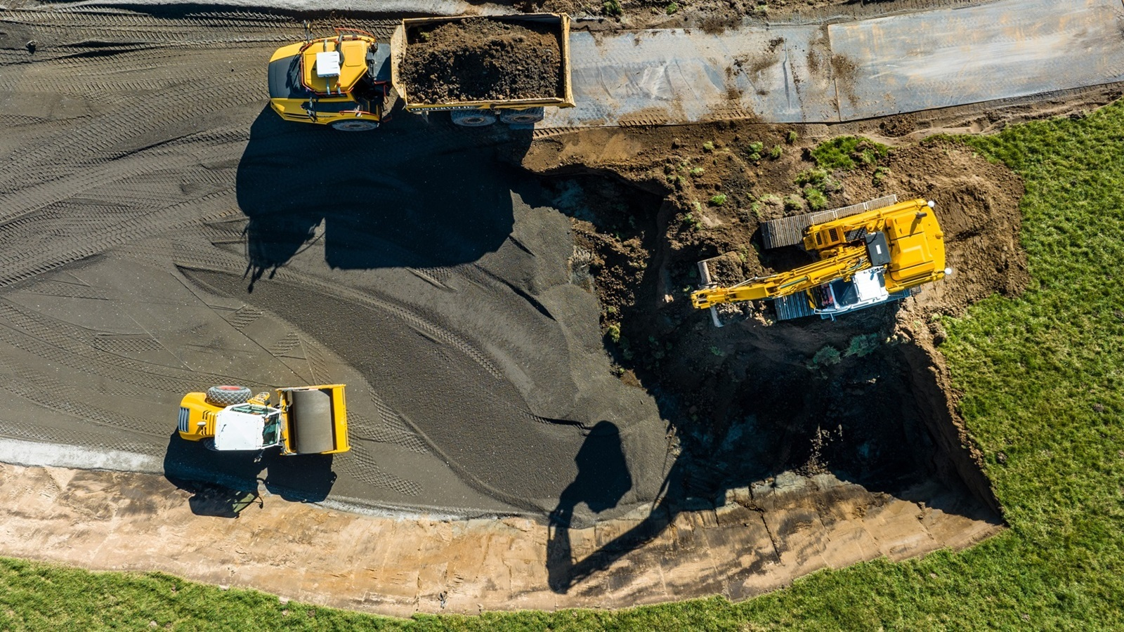 Luchtfoto van wegenbouwwerkzaamheden met gele graafmachines en asfalt
