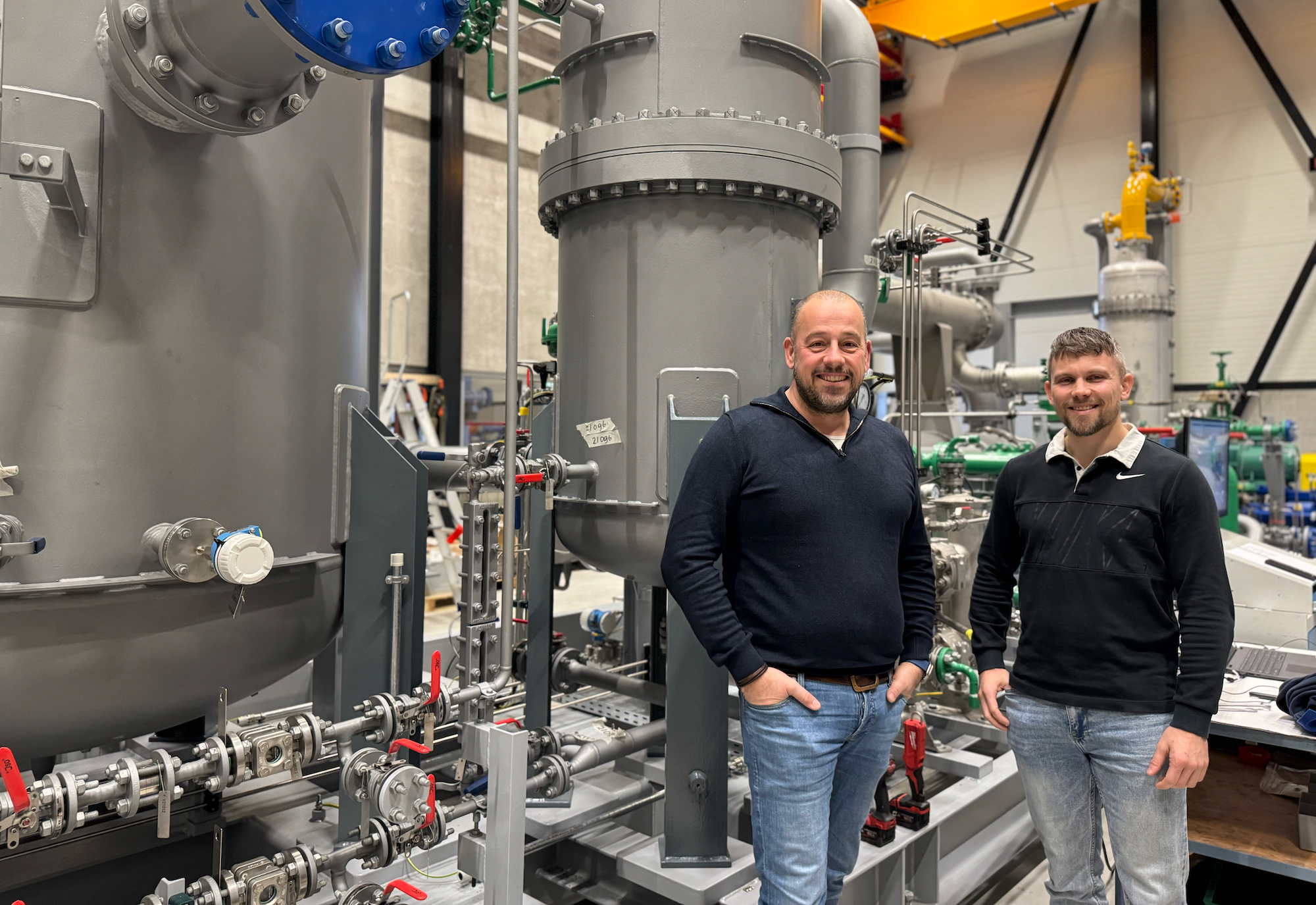 Two men in front of industrial installations
