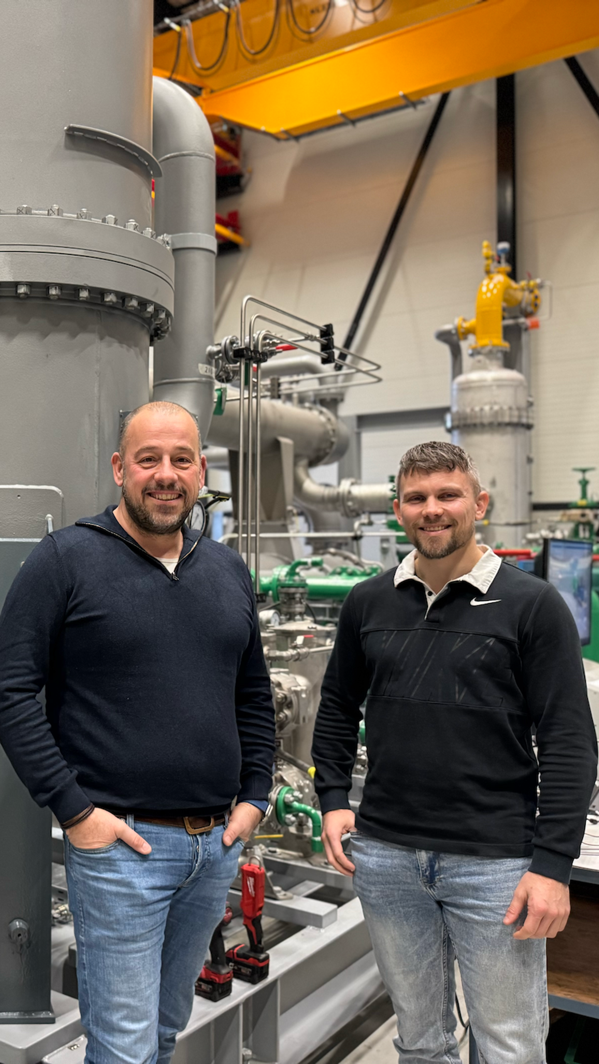 Two men in front of industrial installations