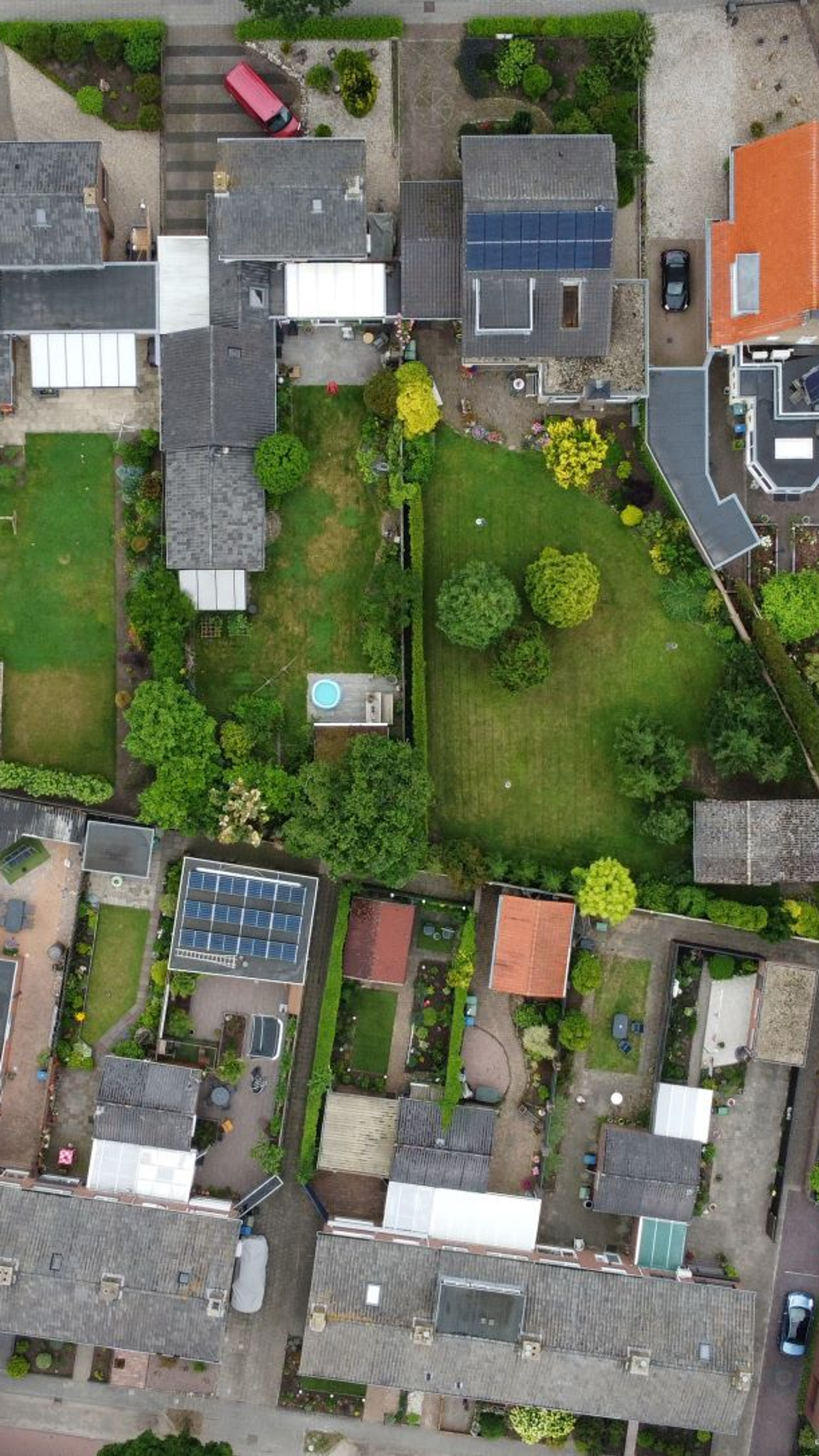 Luchtfoto van een woonwijk met rijtjeshuizen, tuinen en erfafscheidingen – zichtbaar zijn mogelijk onduidelijke grenzen tussen privé- en gemeentegrond (snippergroen).
