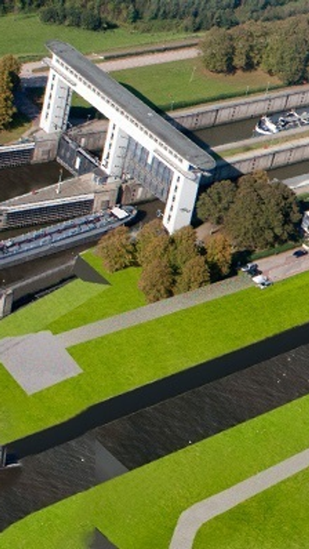Luchtfoto toont monumentale Prinses Beatrixsluis met witte sluisdeuren, binnenvaartschepen in de sluiskolk en groen landschap rondom het Lekkanaal"