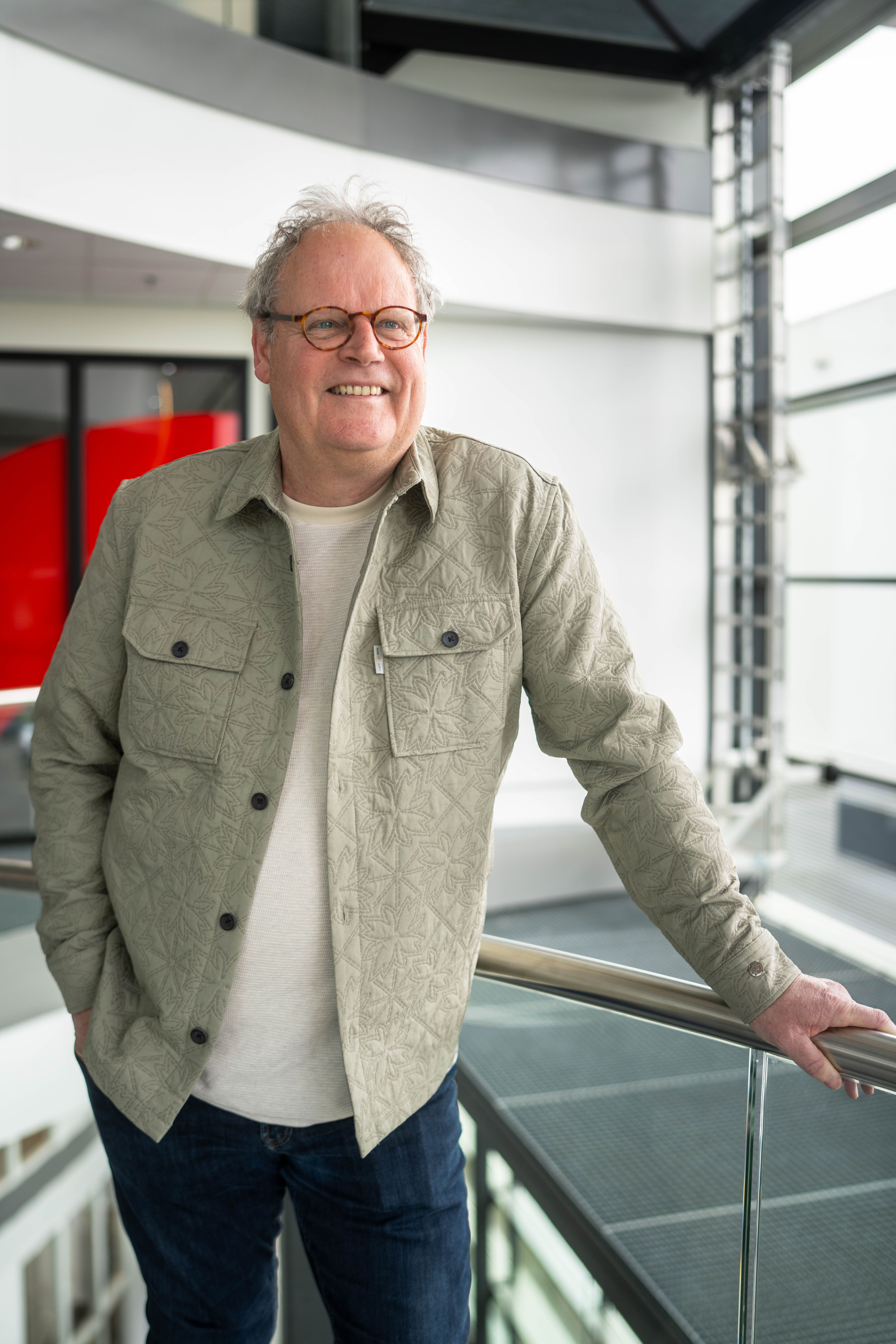Meneer met grijs haar lacht vriendelijk naar de camera