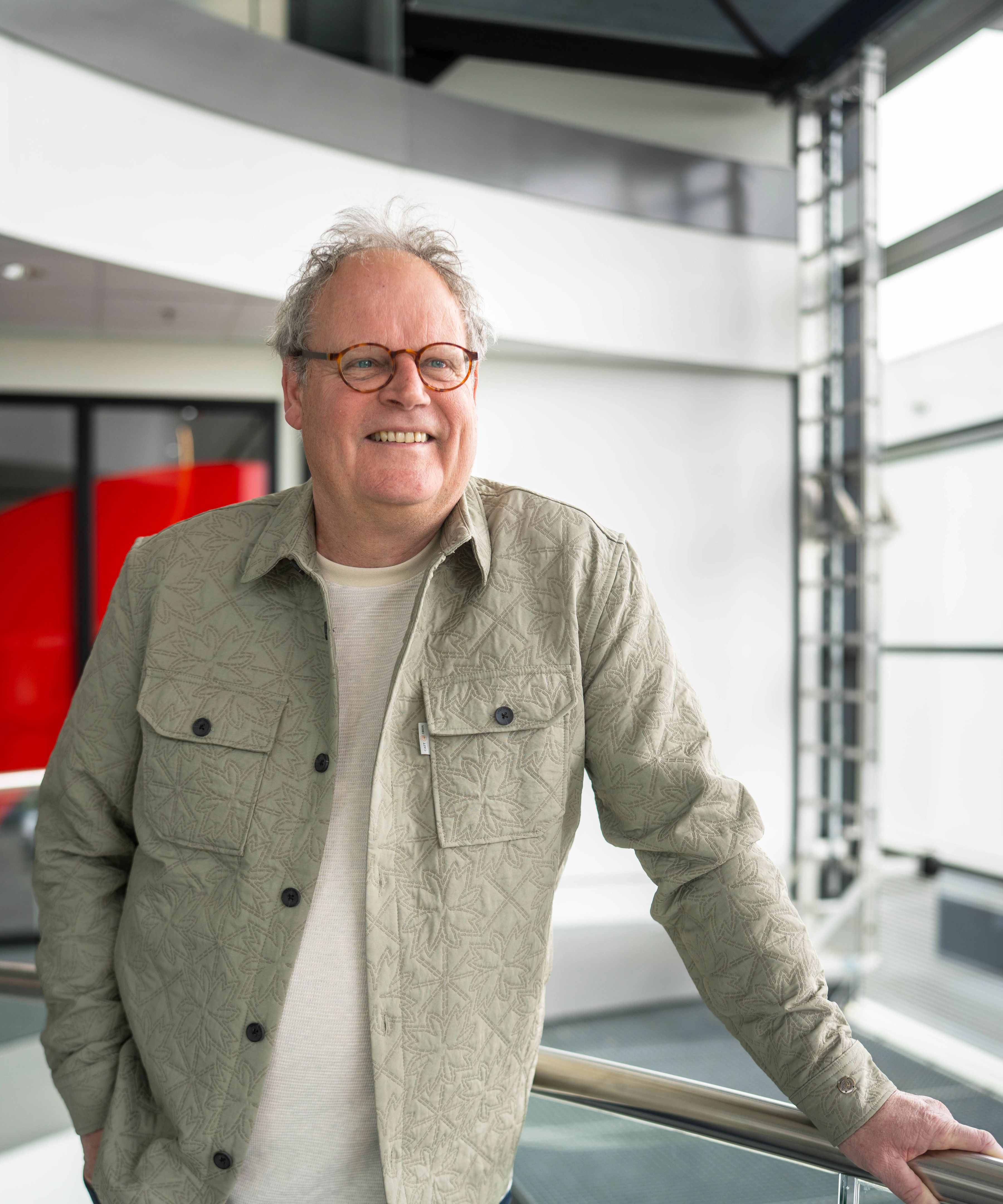 Meneer met grijs haar lacht vriendelijk naar de camera