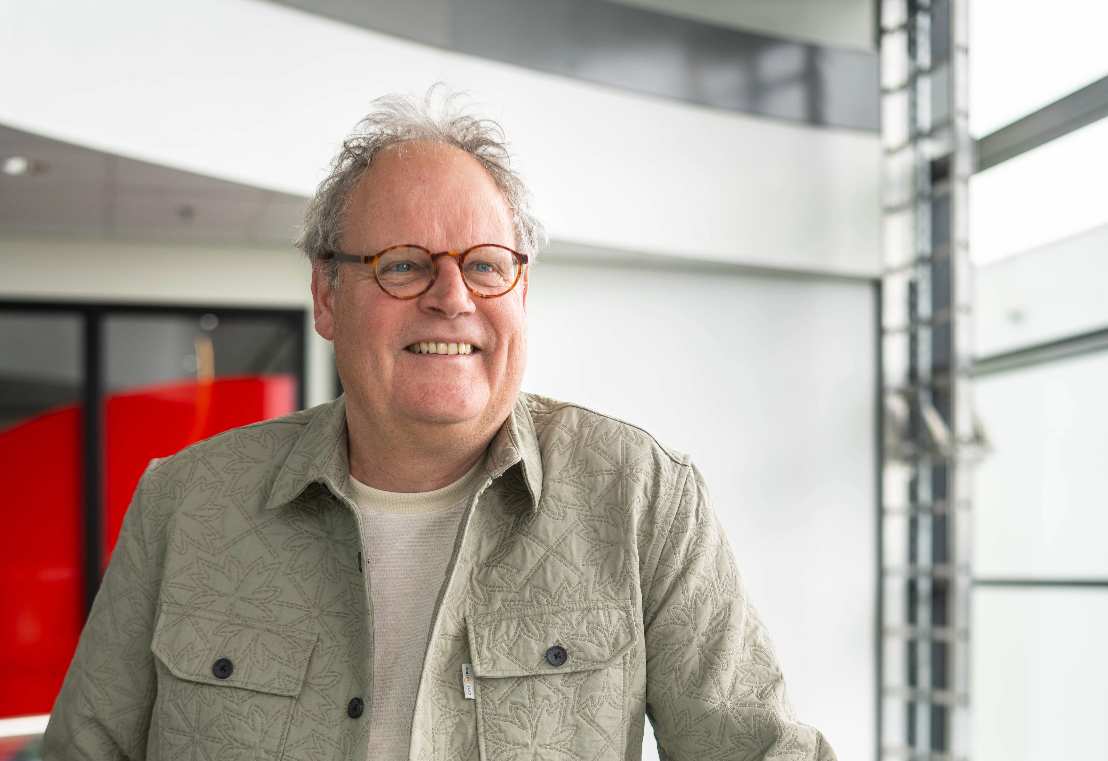 Meneer met grijs haar lacht vriendelijk naar de camera