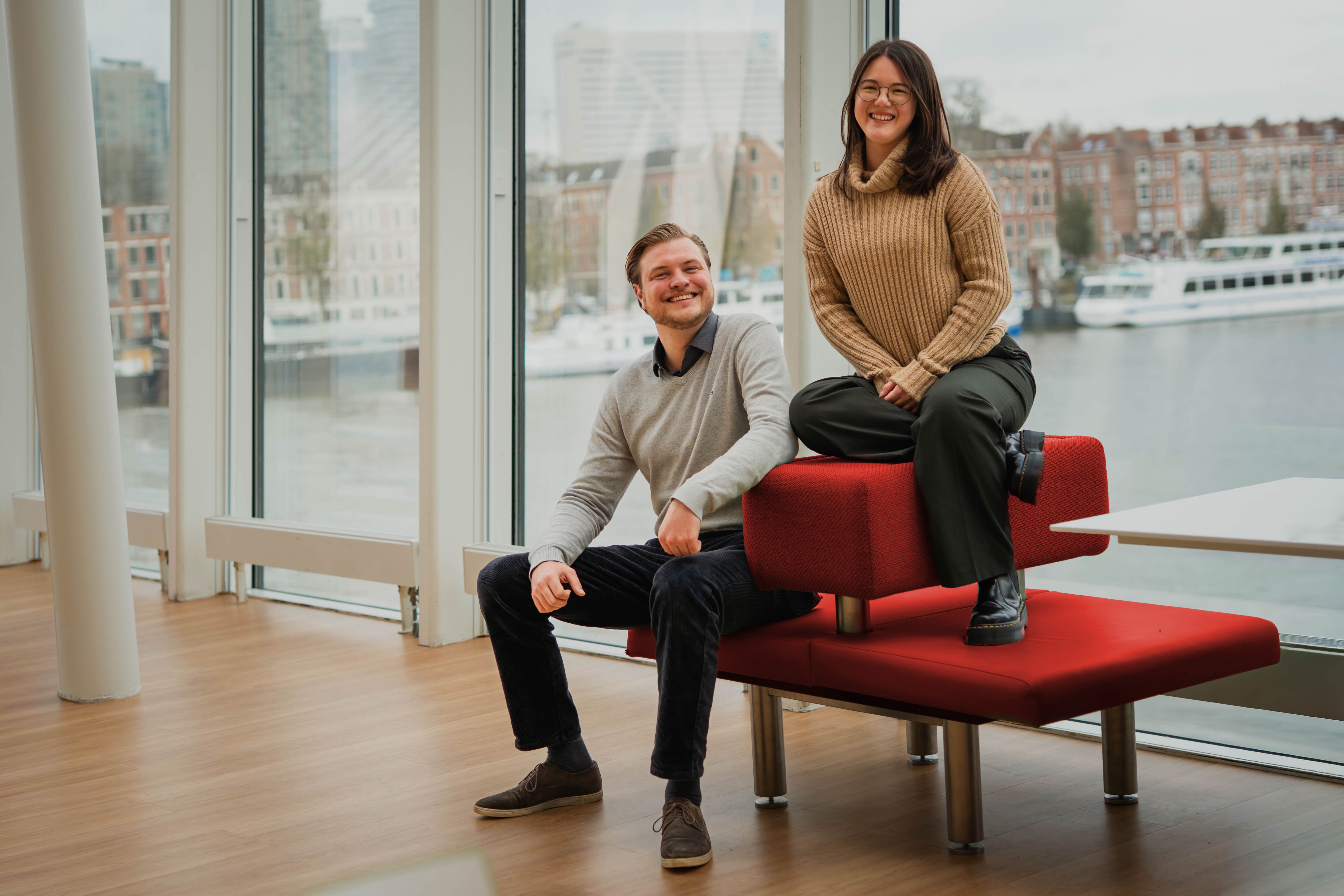 Martijn en Nicole op een rood bankje met uitzicht op Rotterdam