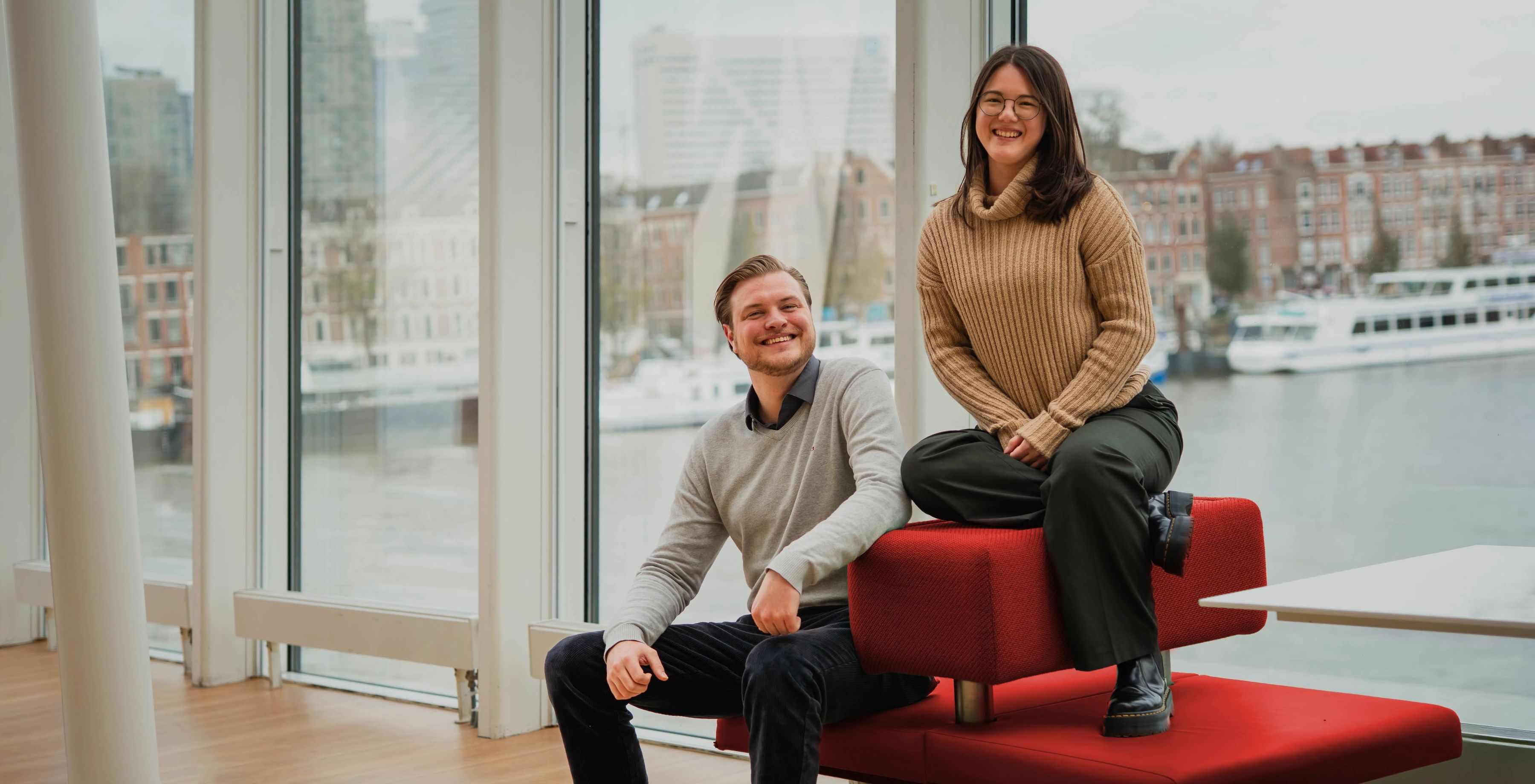 Martijn en Nicole op een rood bankje met uitzicht op Rotterdam