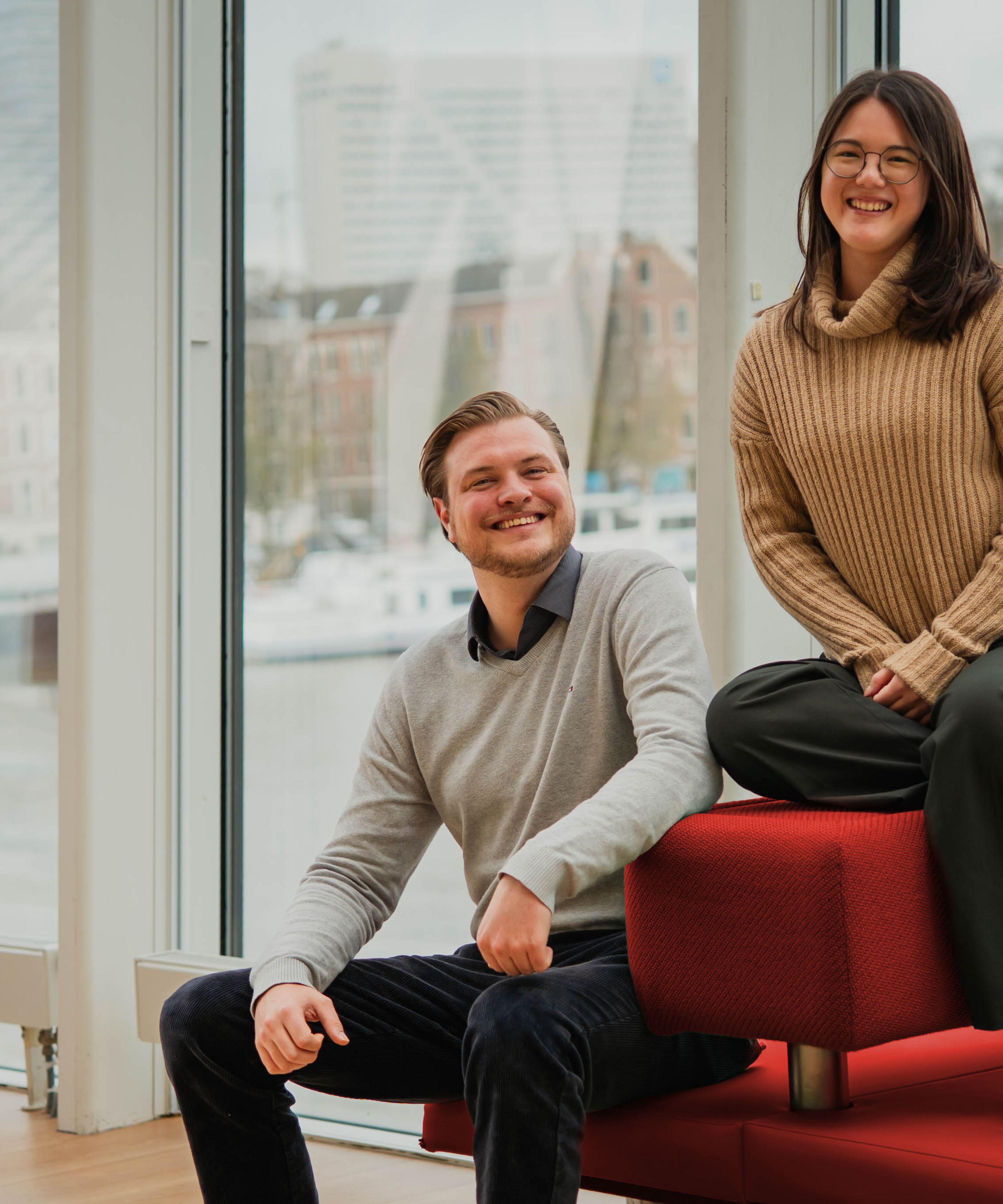 Martijn en Nicole op een rood bankje met uitzicht op Rotterdam