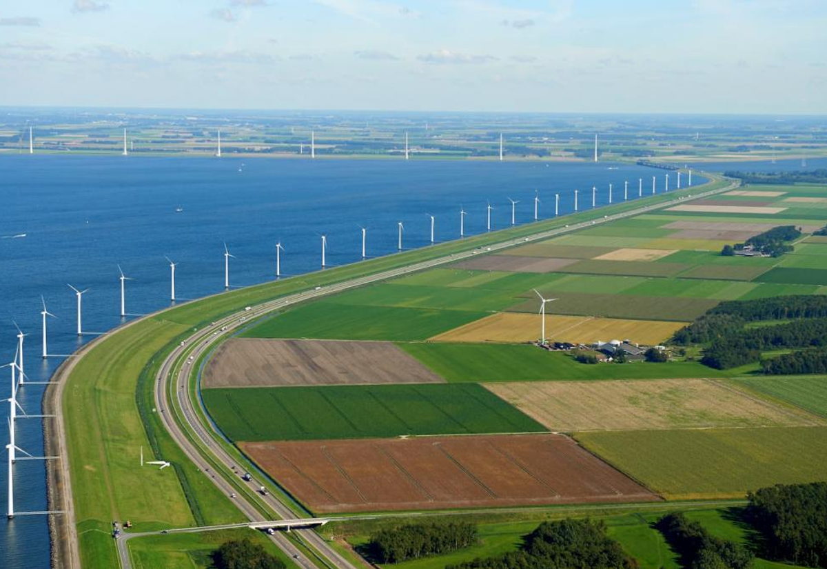 Luchtfoto van dijk langs IJsselmeer met windmolens en agrarisch land