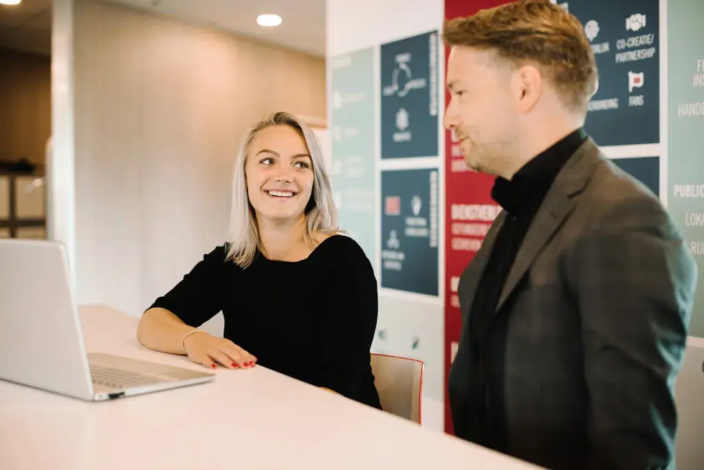 Twee professionals in gesprek bij receptiebalie in modern kantoor