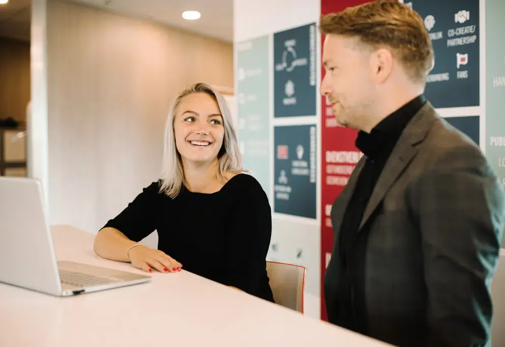Twee professionals in gesprek bij receptiebalie in modern kantoor