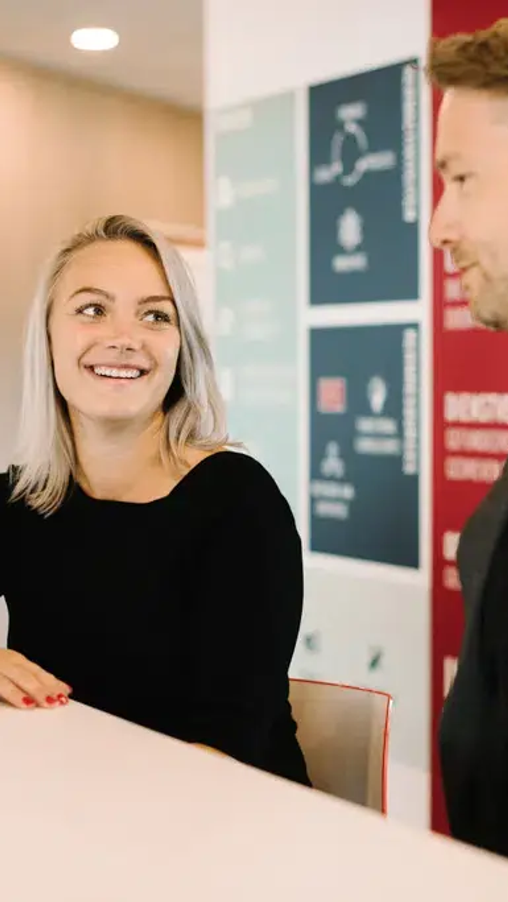 Twee professionals in gesprek bij receptiebalie in modern kantoor