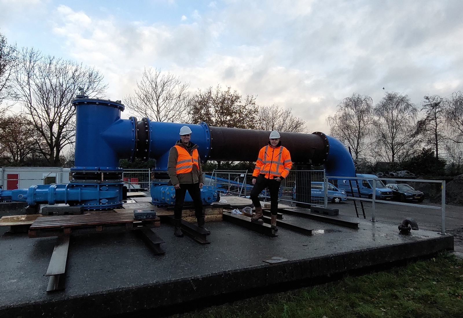 Twee werknemers in veiligheidspakken bij grote blauwe leidinginstallatie