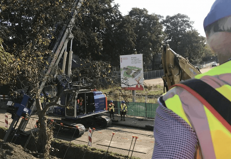 Bouwplaats met graafmachine en werknemer in veiligheidsvest