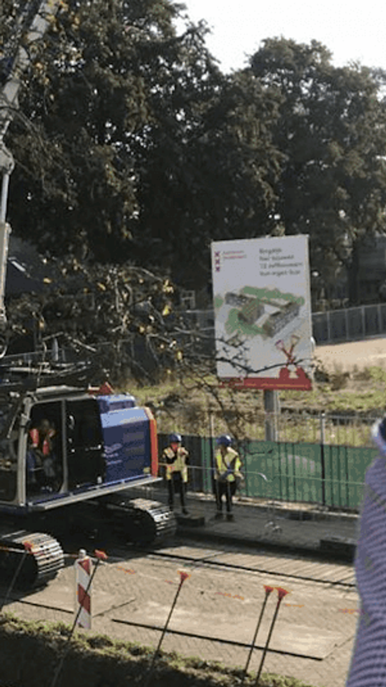 Bouwplaats met graafmachine en werknemer in veiligheidsvest